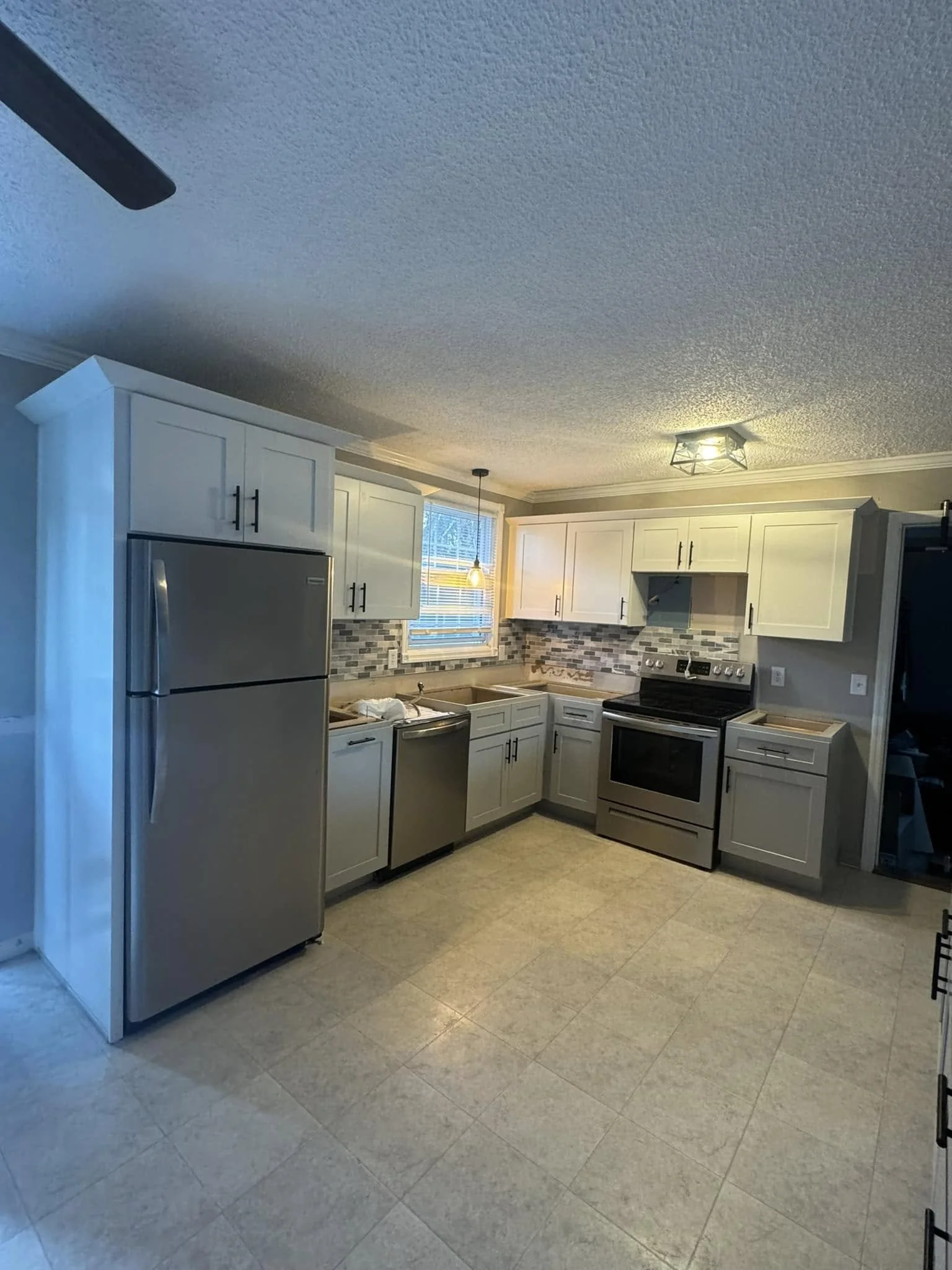 Kitchen renovation in Southaven, MS featuring custom white cabinets, updated countertops, and stainless steel appliances by DeSoto Renovations.