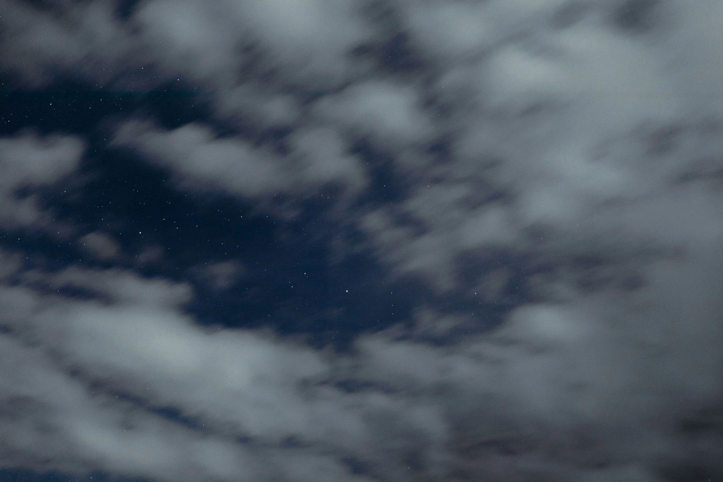 A blue night sky with silver clouds and stars out in space