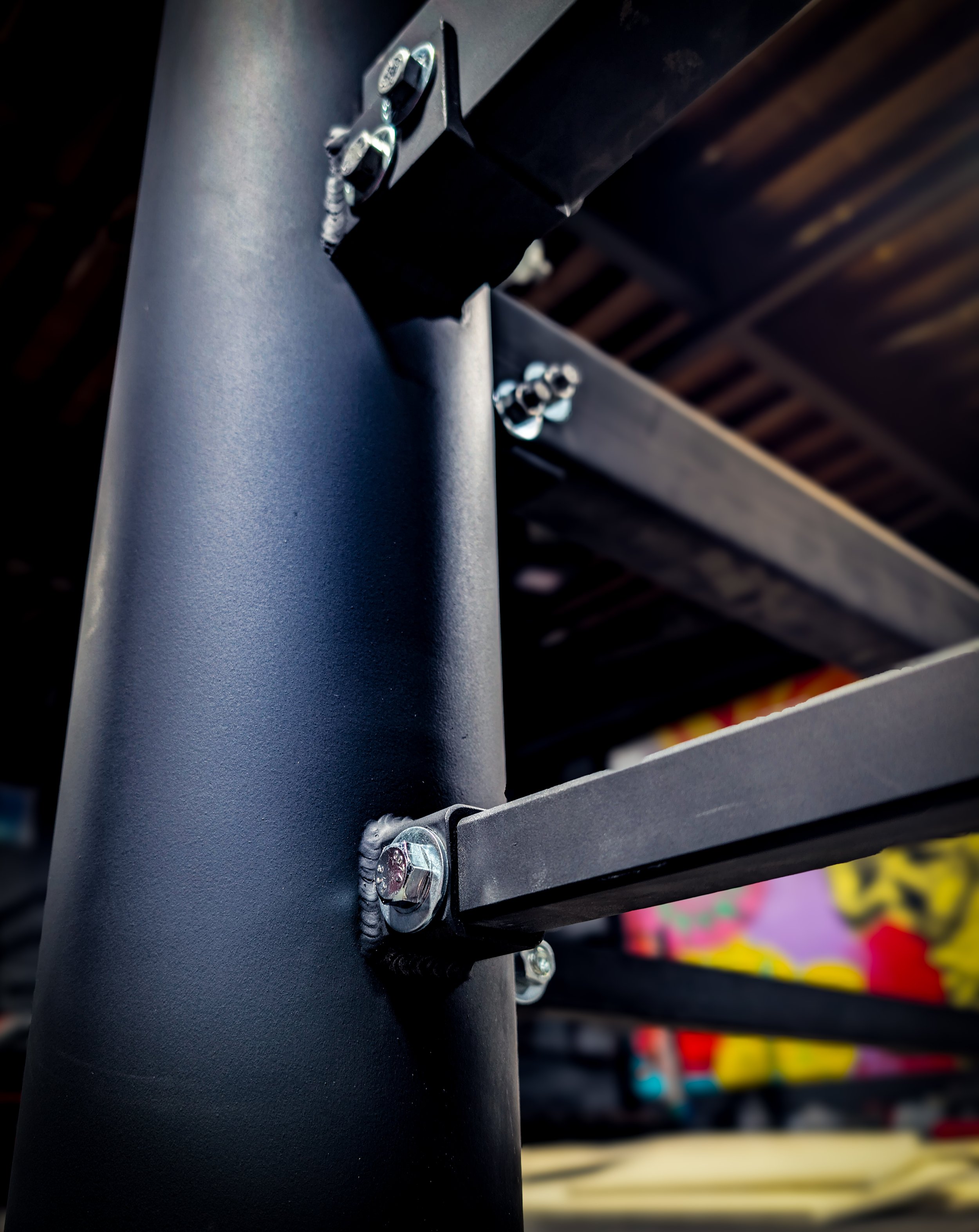 Close-up of a black metal leg with bolts and brackets, part of custom boxing ring.