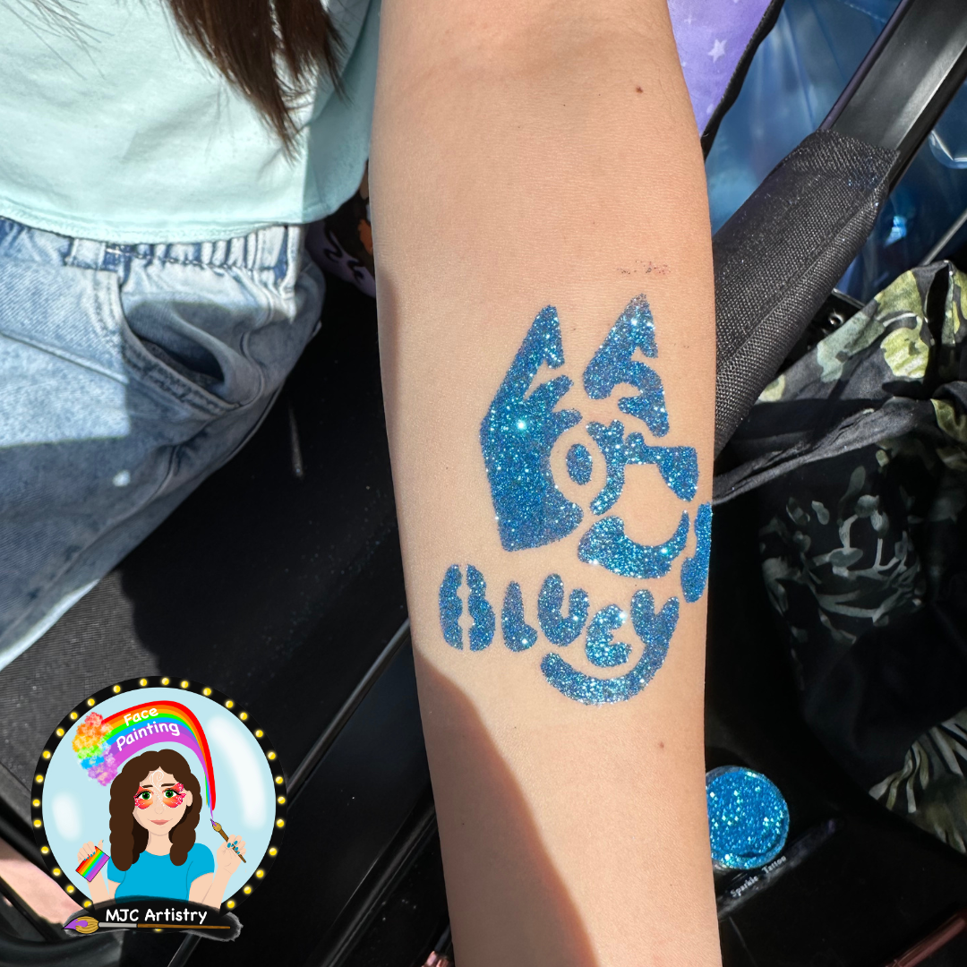 Blue glitter face painting on a person's forearm in the shape of an abstract flame with a face drawing, indicating a creative design for a face-painting event.