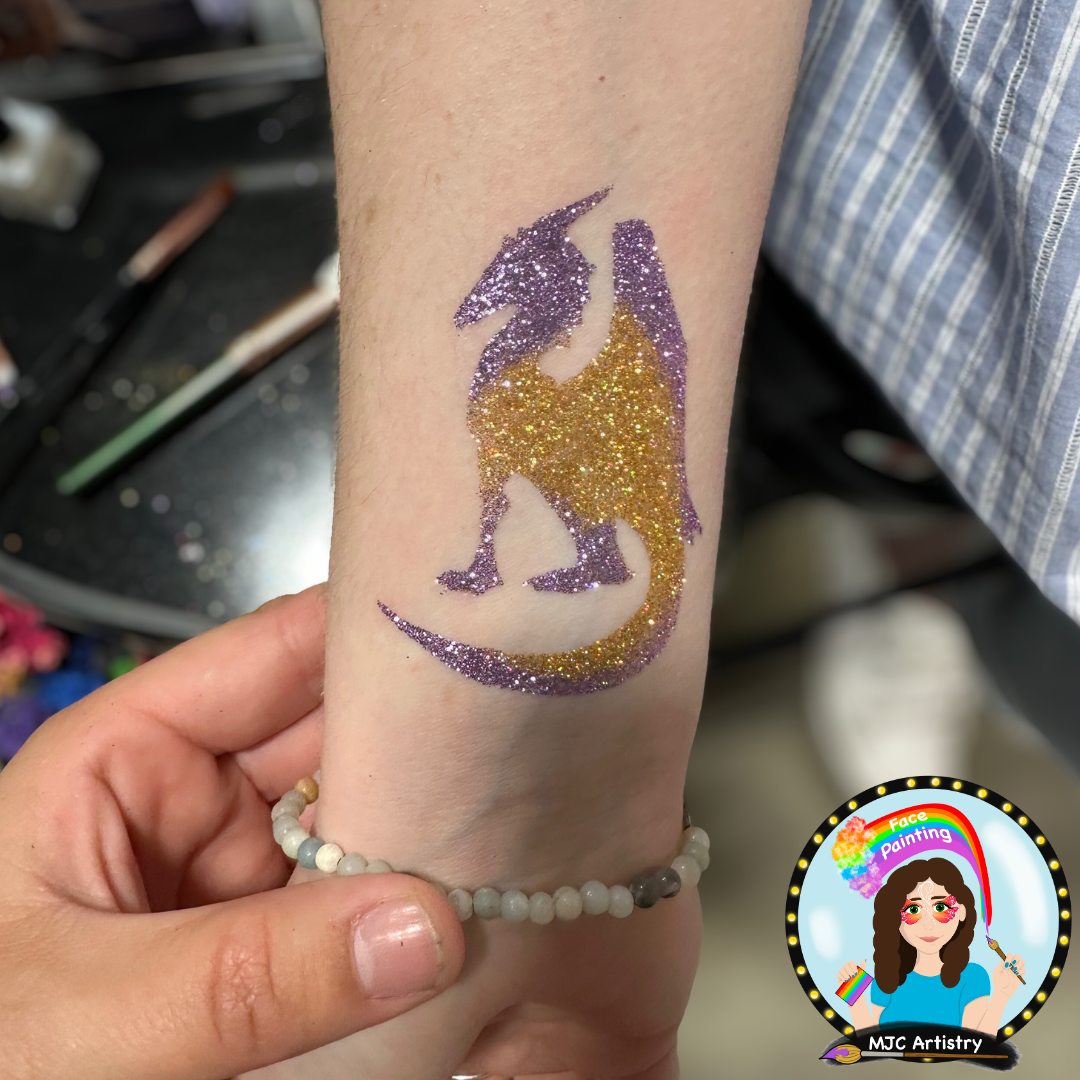 Glitter tattoo of a purple and gold dragon on a person's forearm.