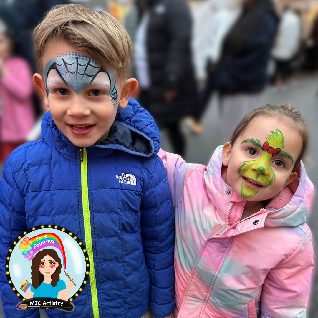 Two children with face paint, a blue spider man and girly grinch face painting smiling at the camera at a community event in Vancouver BC. 