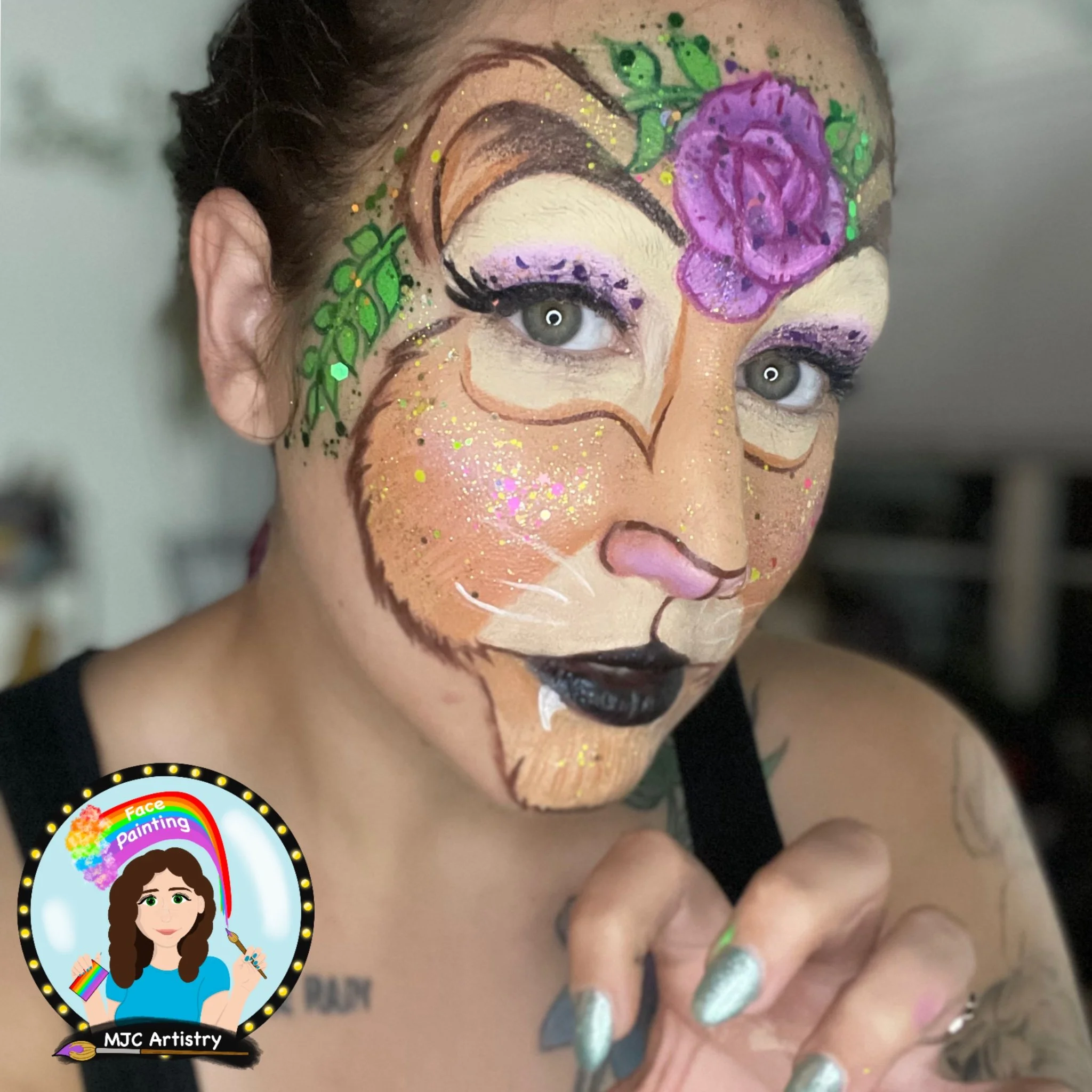 A person with face paint resembling a lion's face in warm hues with purple and pink flowers, green leaves, and glitter details.