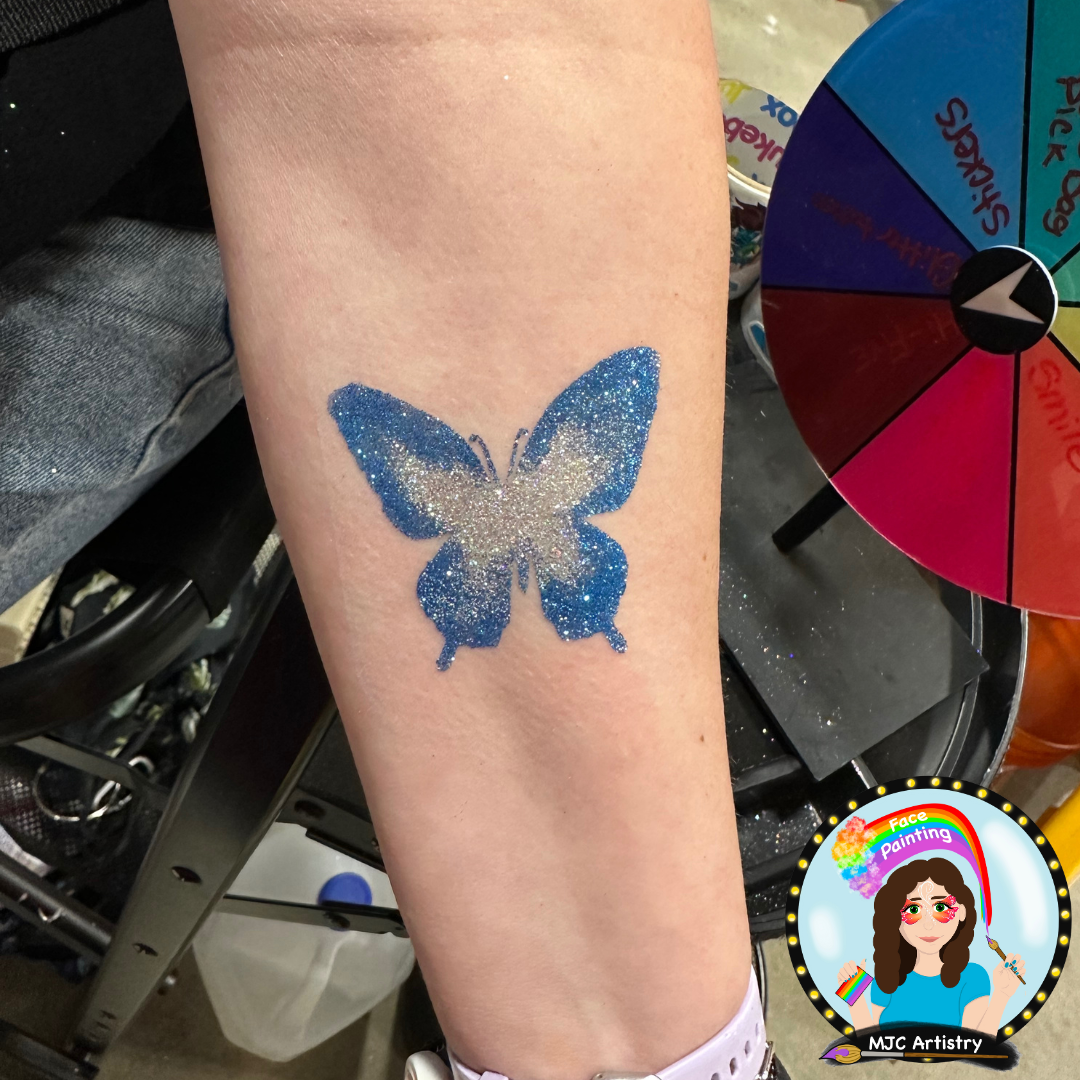 A person's arm with a blue and silver glitter butterfly temporary tattoo.