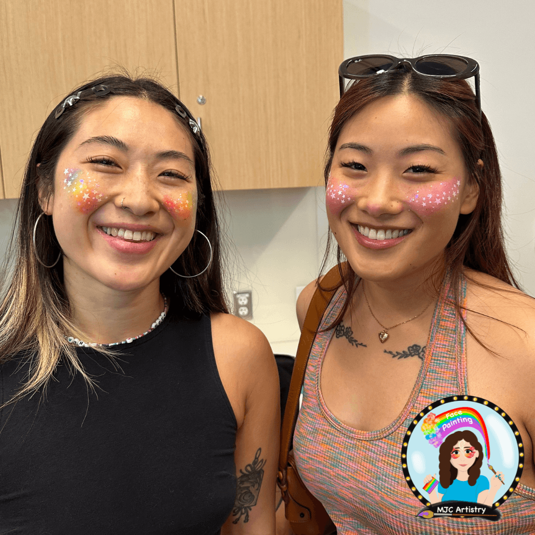 two people with long hair and subtle makeup like face paint on their cheeks smiling
