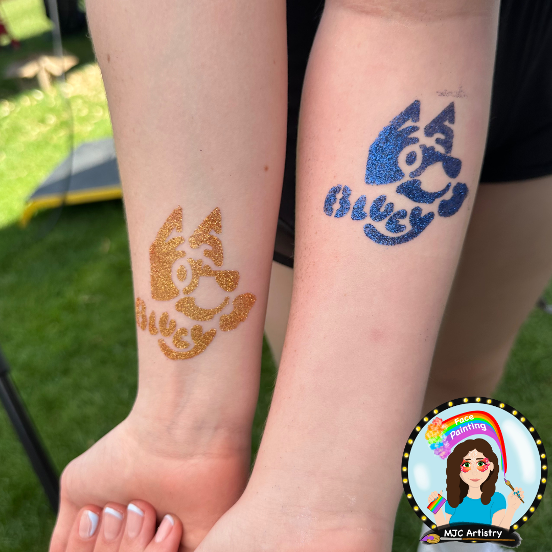 Two forearms with bluey glitter tattoos s, one in gold glitter and the other in blue glitter, outdoors on a sunny day at a public event in Vancouver. 