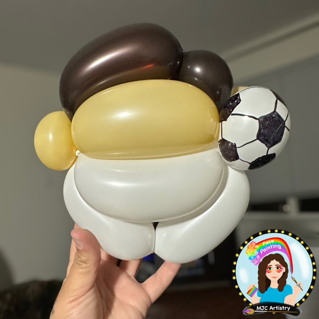 Balloon sculpture of a person wearing a soccer jersey, holding a soccer ball, made of various colored balloons.
