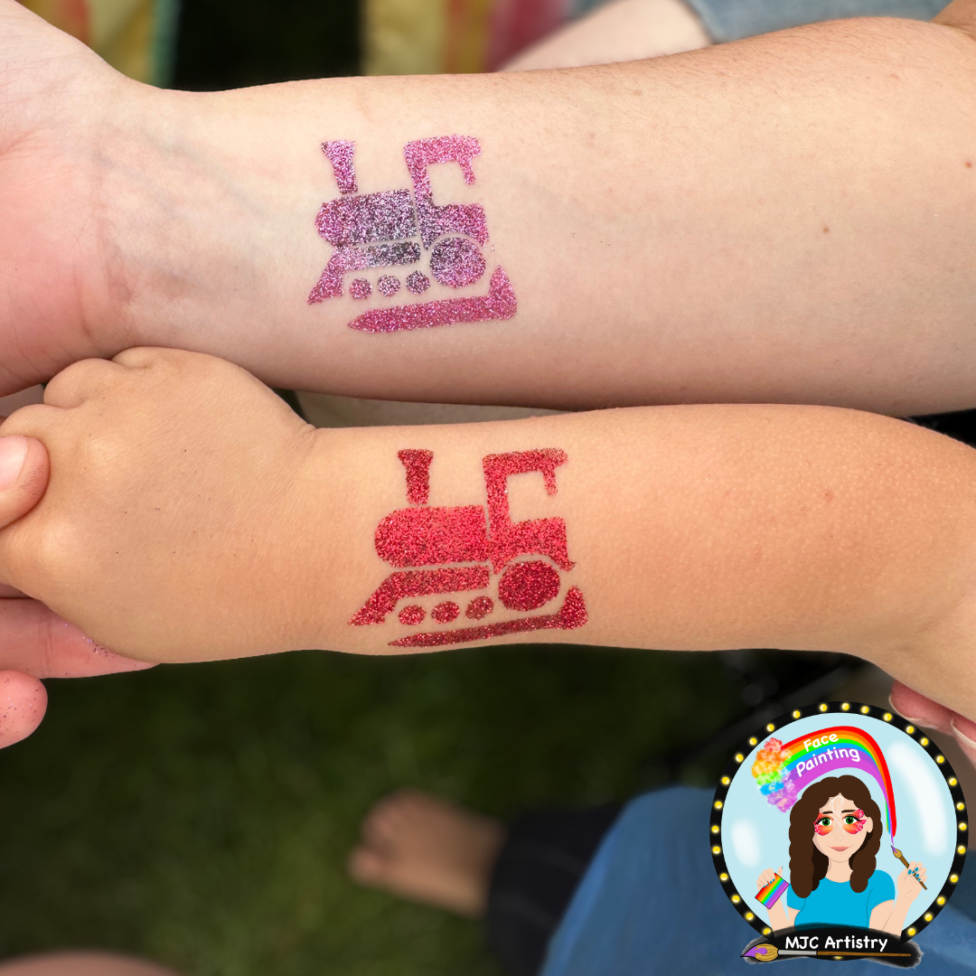 Two arms displaying glitter tattoo designs of a washing machine, one on each arm, with the arms crossing each other. Glitter tattoos at a public event in Vancouver BC.