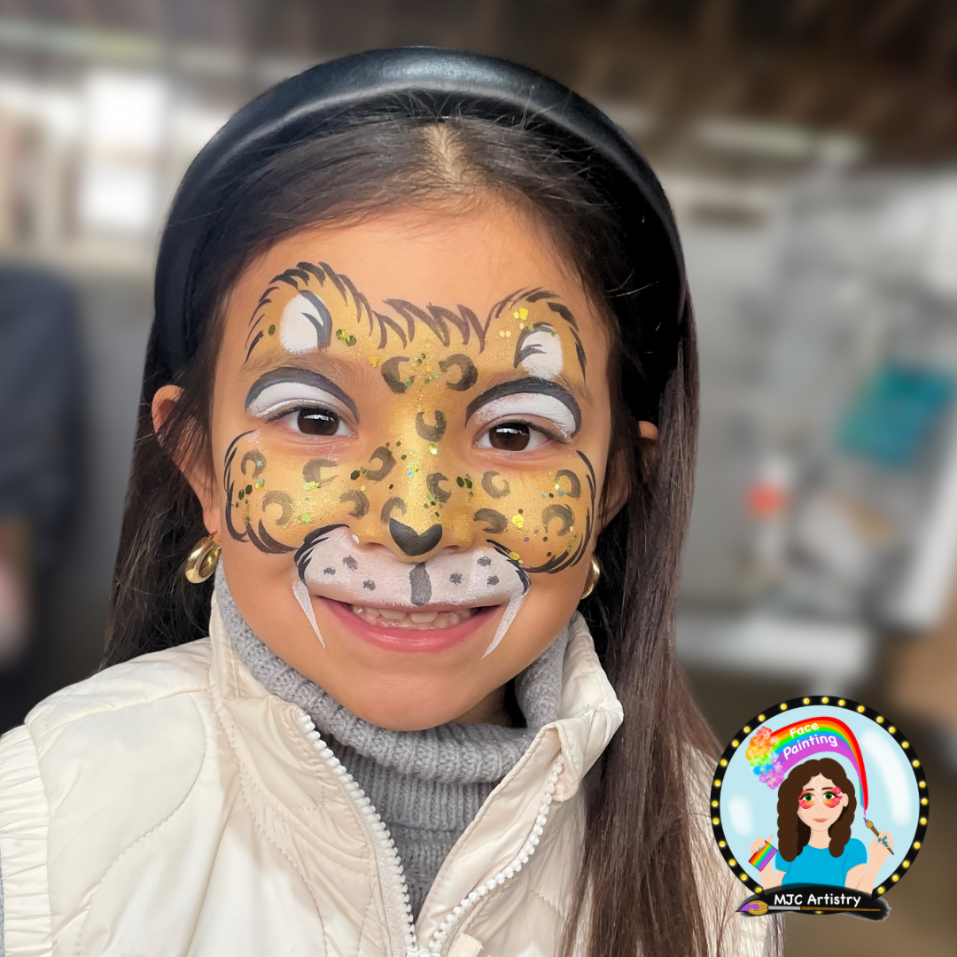 Girl with cheetah face paint smiling wearing a white jacket and gray turtleneck. Face painting at Vancouver birthday party.