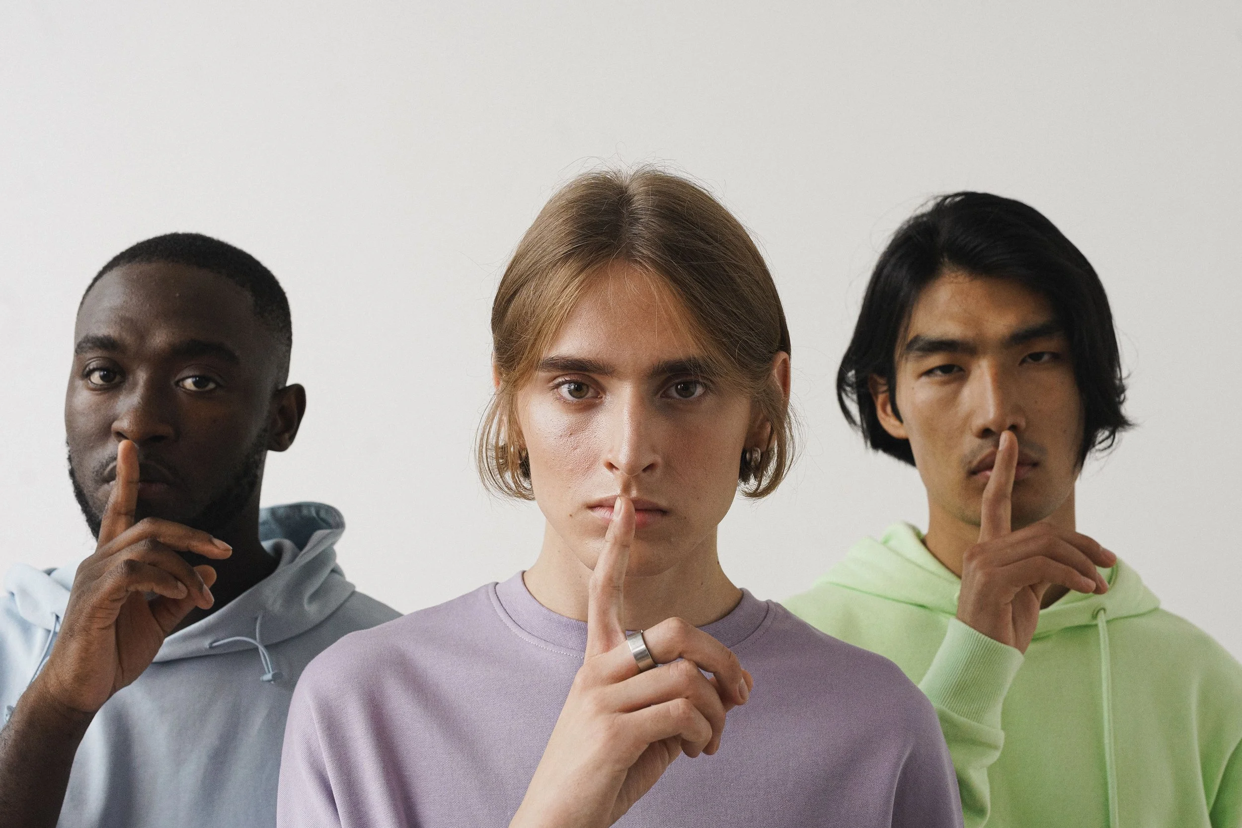 Three young adults making a shushing gesture in a studio setting, highlighting diversity.  More info  Share