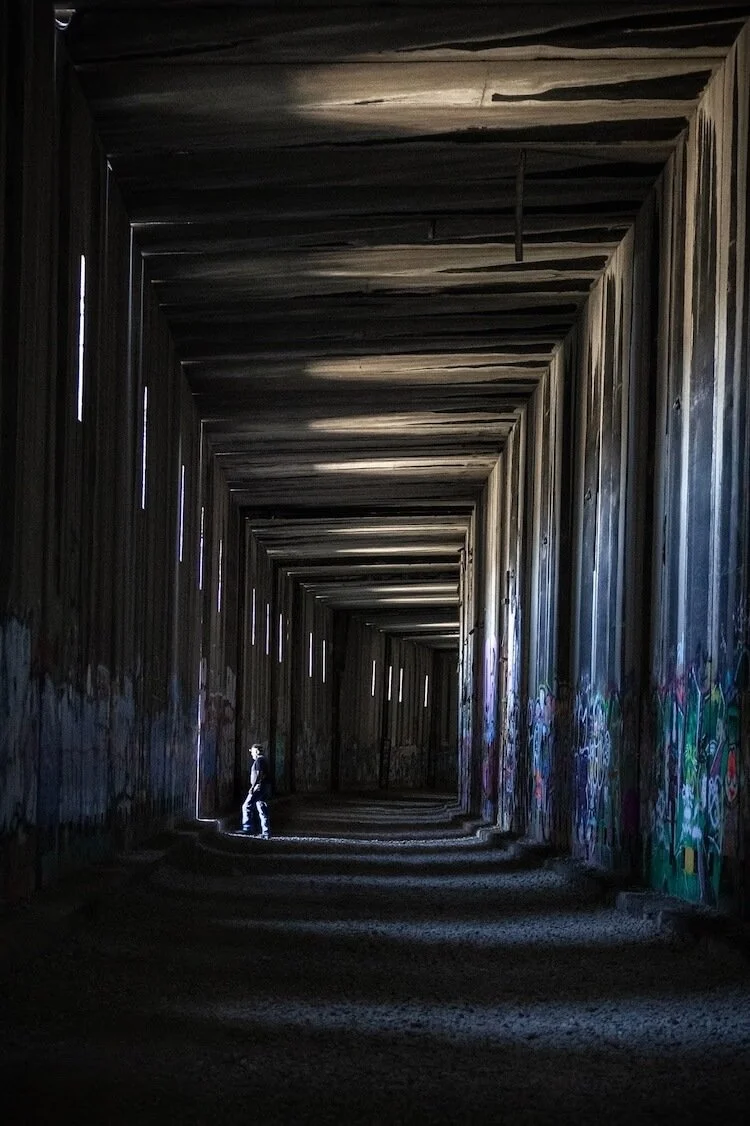 Abandoned train tunnel with hiker looking out