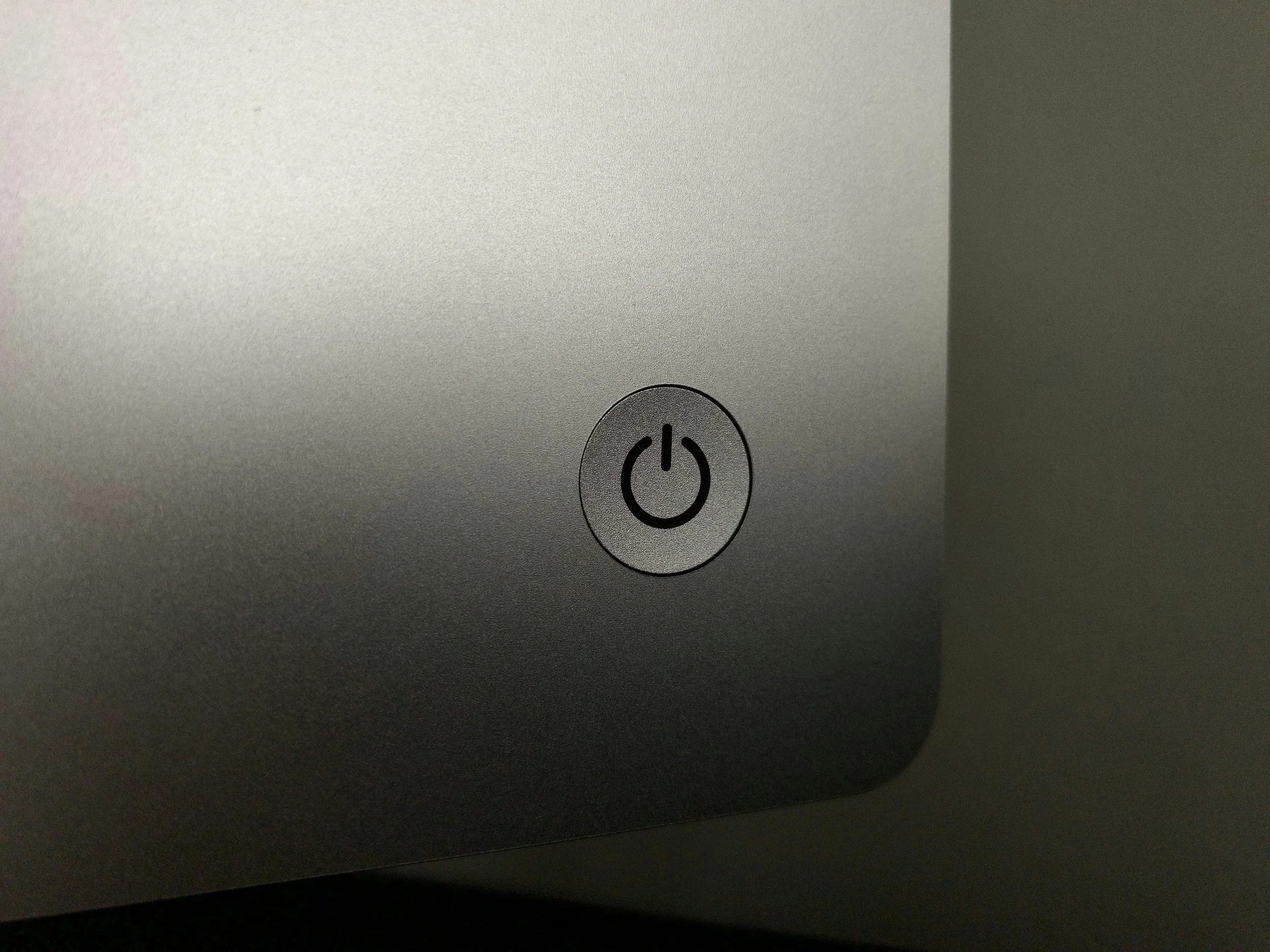 Close-up of a computer or device power button on a metallic surface