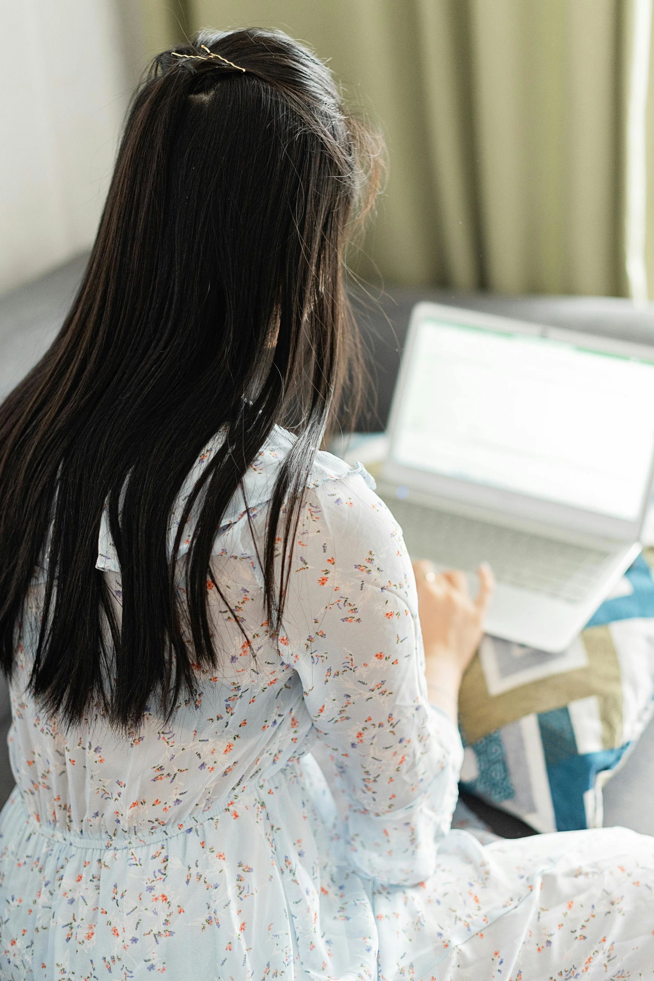 Asian woman using laptop in a bright home office, representing virtual therapy or online counseling