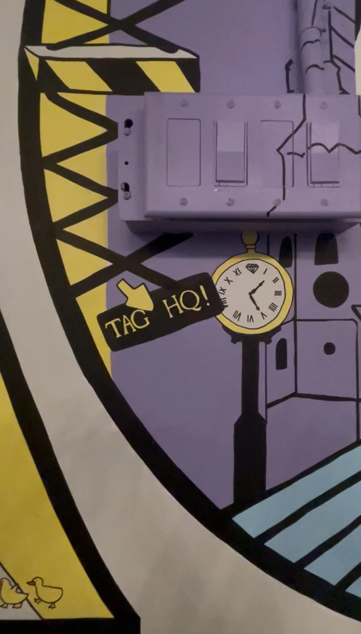 Colorful wall with a coffee machine, a clock showing approximately 4:55, and a sign that says "TAG HQ!" with a yellow arrow pointing to the right. Mural created for Third And Grove in Downtown Boston.