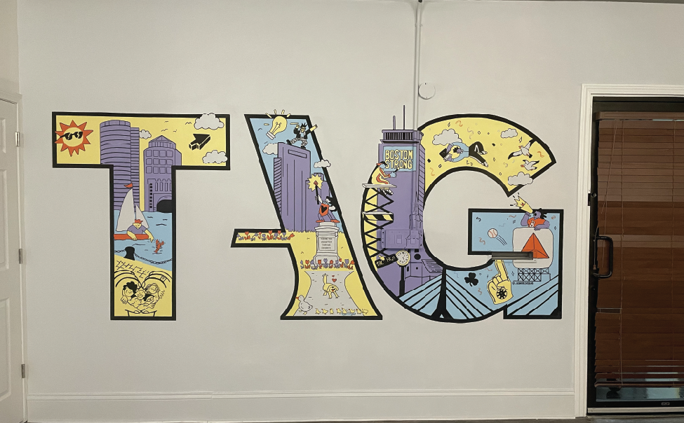 Colorful mural spelling out 'TAG' with urban and outdoor scenes inside each letter, including buildings, people, boats, and animals.