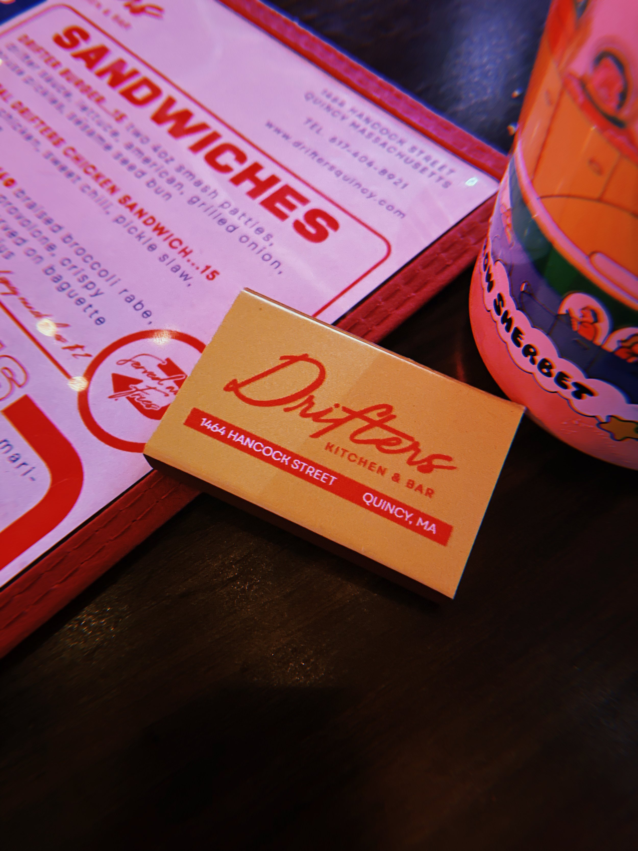 Business card for Dufresne Kitchen & Bar at 1404 Hancock Street, Quincy, MA, with a menu for sandwiches and a colorful cup beside it.