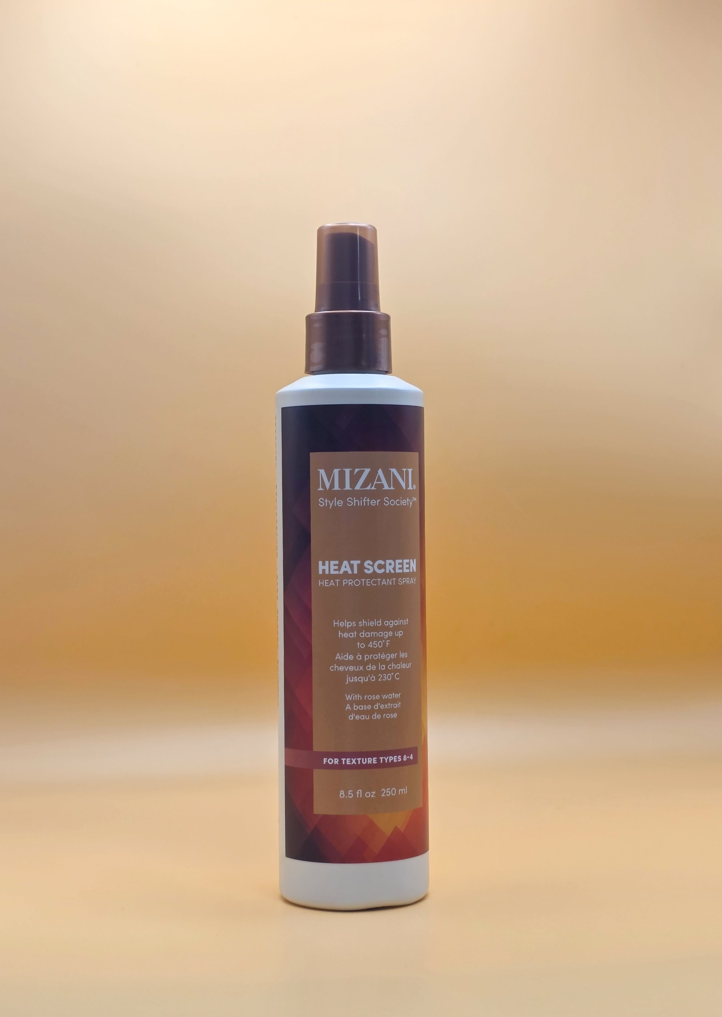 A white spray bottle labeled 'MIZANI Heat Screen Heat Protectant Spray' with a brown cap, placed on a yellow background.