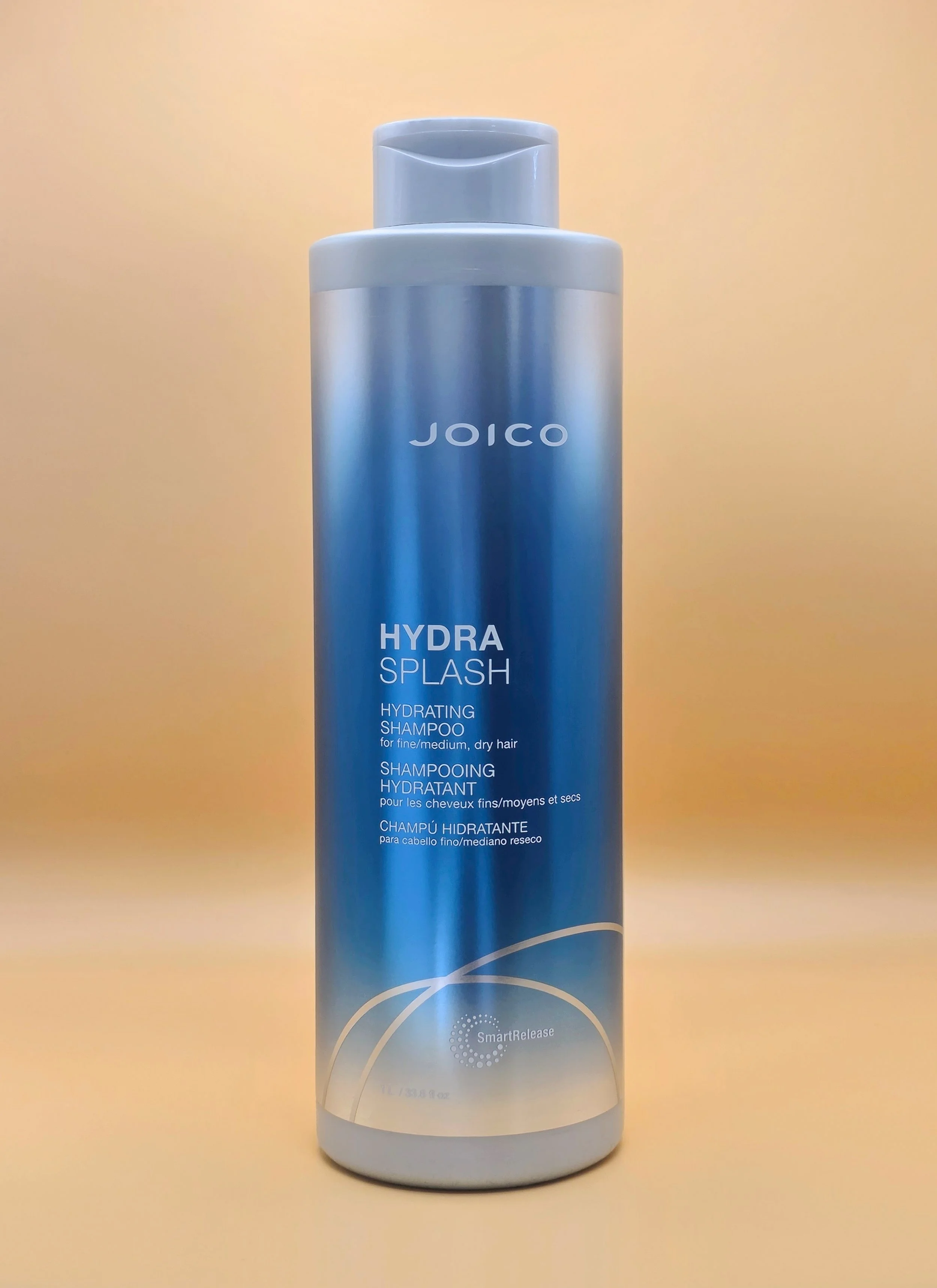 A blue bottle of Joico Hydra Splash Hydrating Shampoo for fine, medium, and dry hair, standing against a plain background.