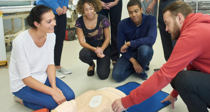 Group of people practicing CPR on a medical mannequin in a training session.