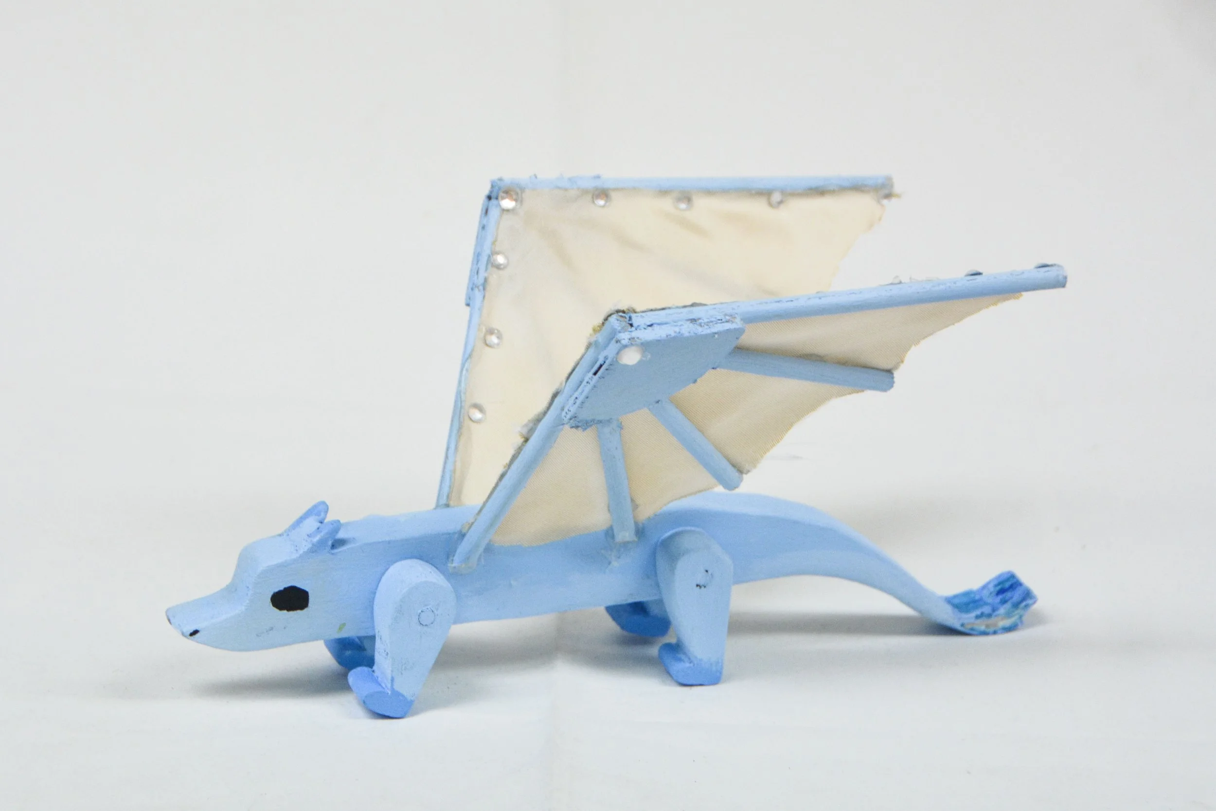 Wooden toy of a blue and white dog with movable legs and a canine face, designed as a chair with an adjustable backrest.