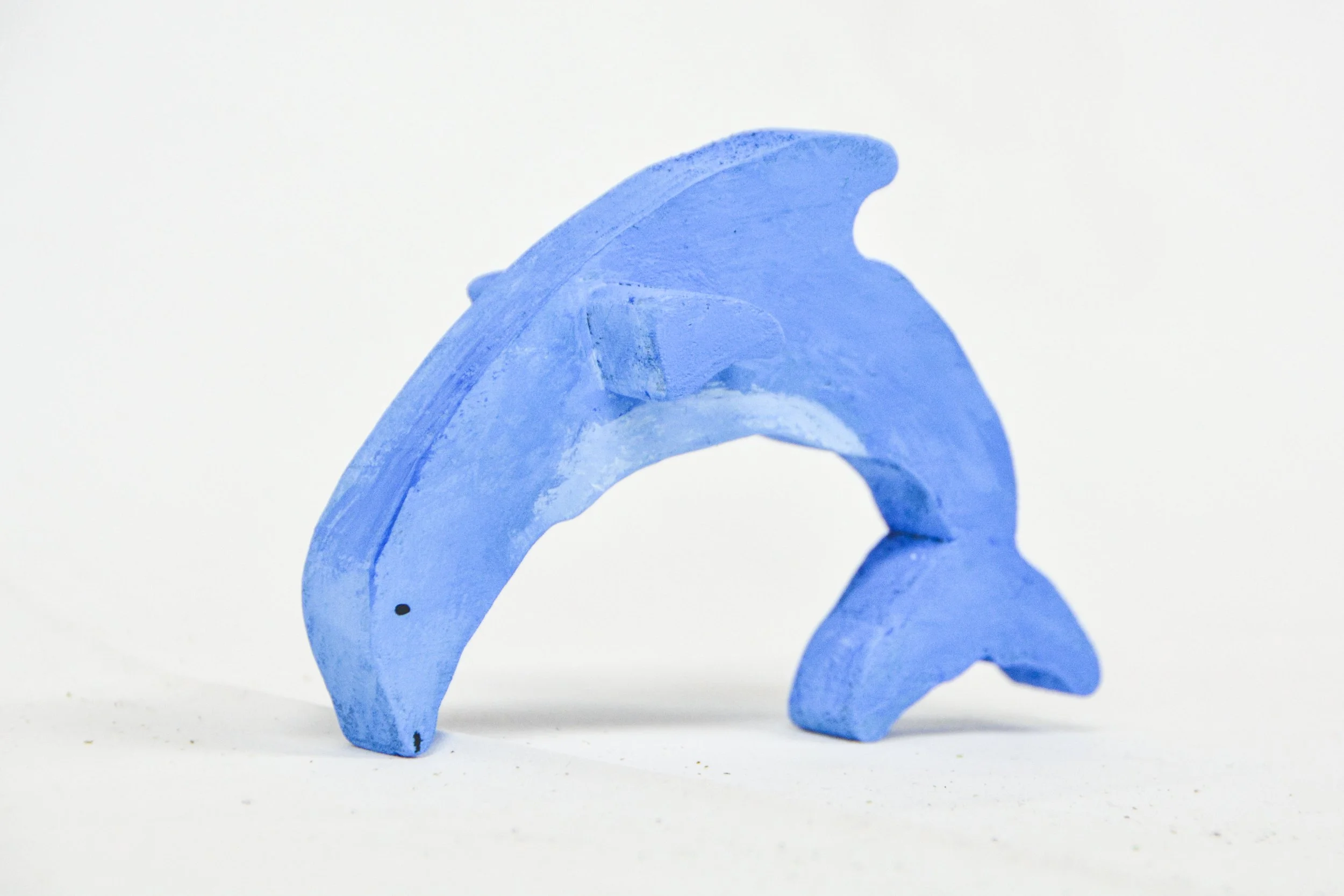 Blue wooden dolphin figurine on a white background.