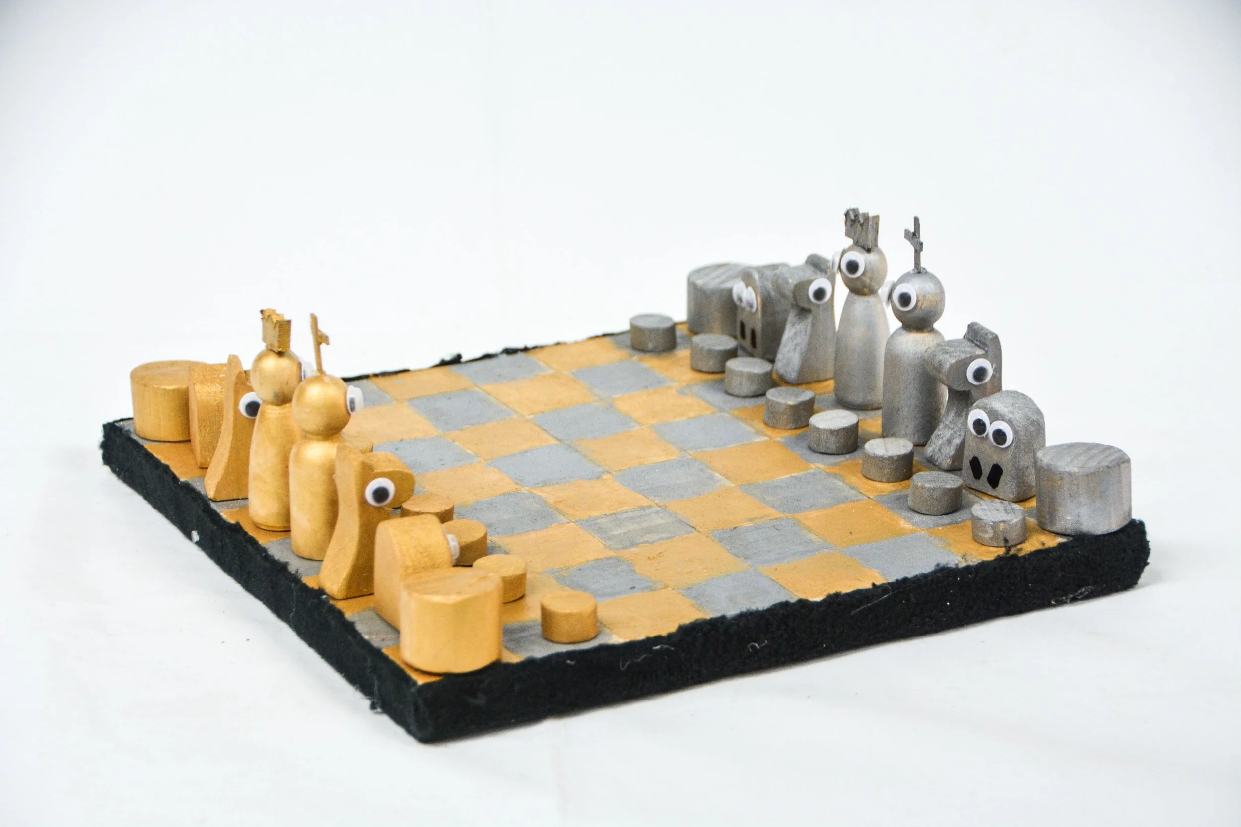 Wooden chess set with googly eyes on the pieces, arranged on a checkered board with a black border, against a plain white background.