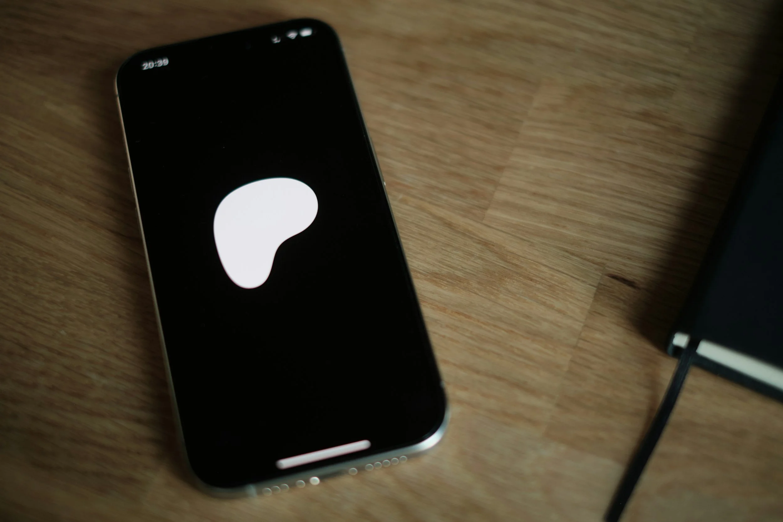 A smartphone lying on a wooden surface displaying a white question mark on a black background.