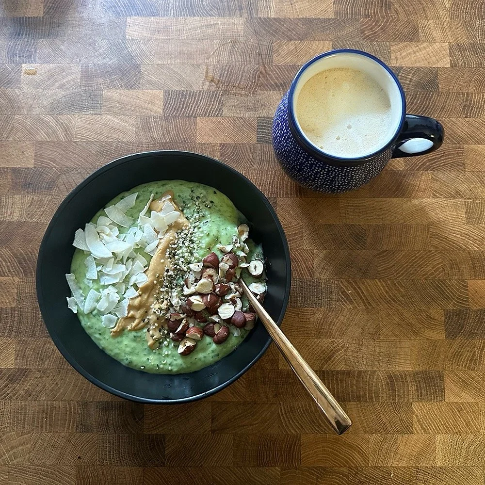 Photo of a green smoothie bowl sprinkled with coconut, peanut butter, hemp seeds and hazelnuts