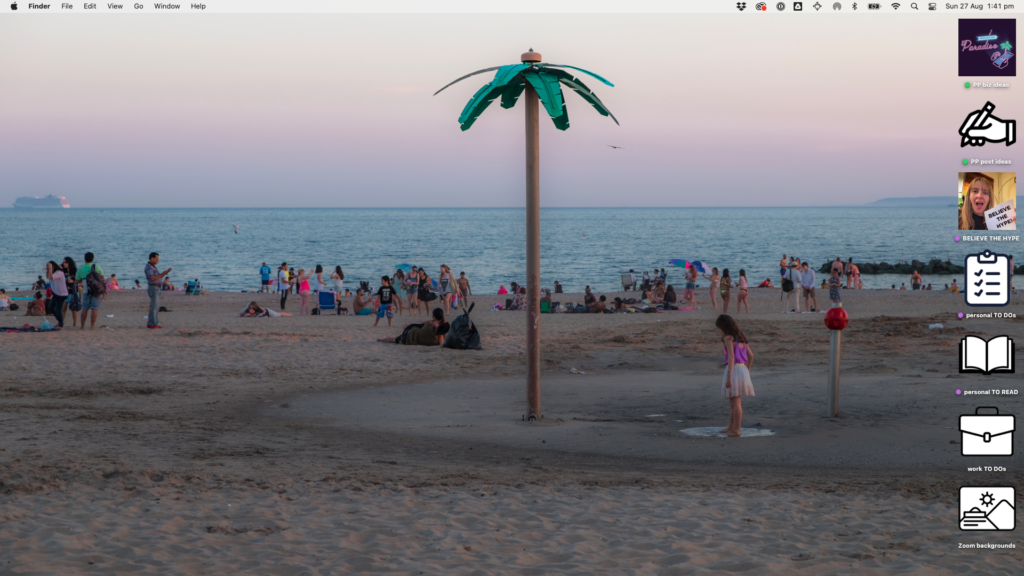 Desktop background photo of a dusk beach scene full of people relaxing and a metal palm tree planted in the middle