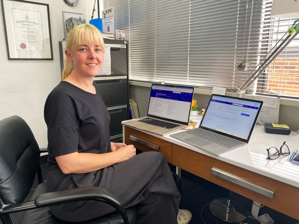 Photo of a smiling woman in front of two laptops