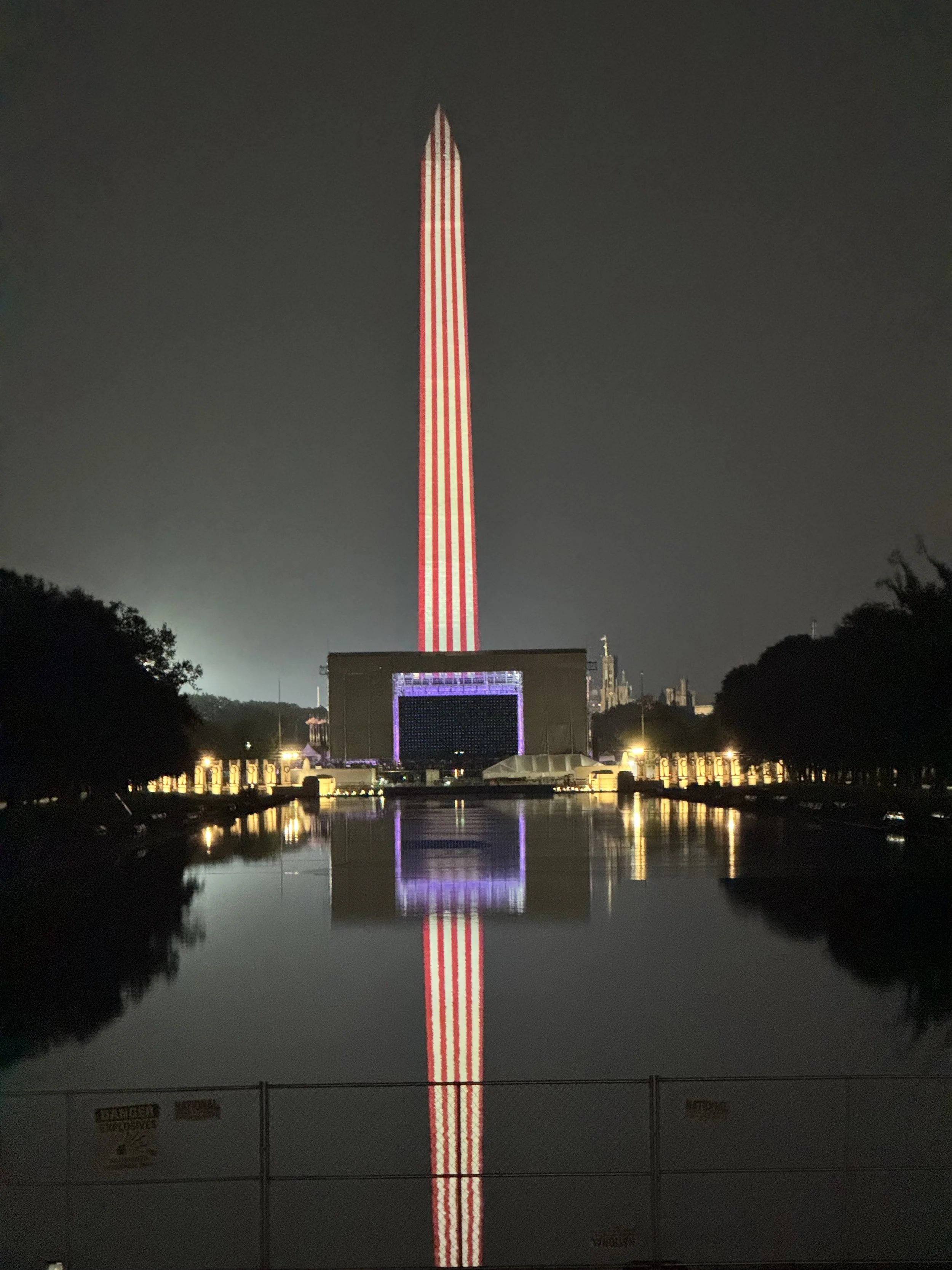 Washington Monument glowing like a birthday candle for America's 250th birthday, reflected across the Reflecting Pool in Washington, D.C.