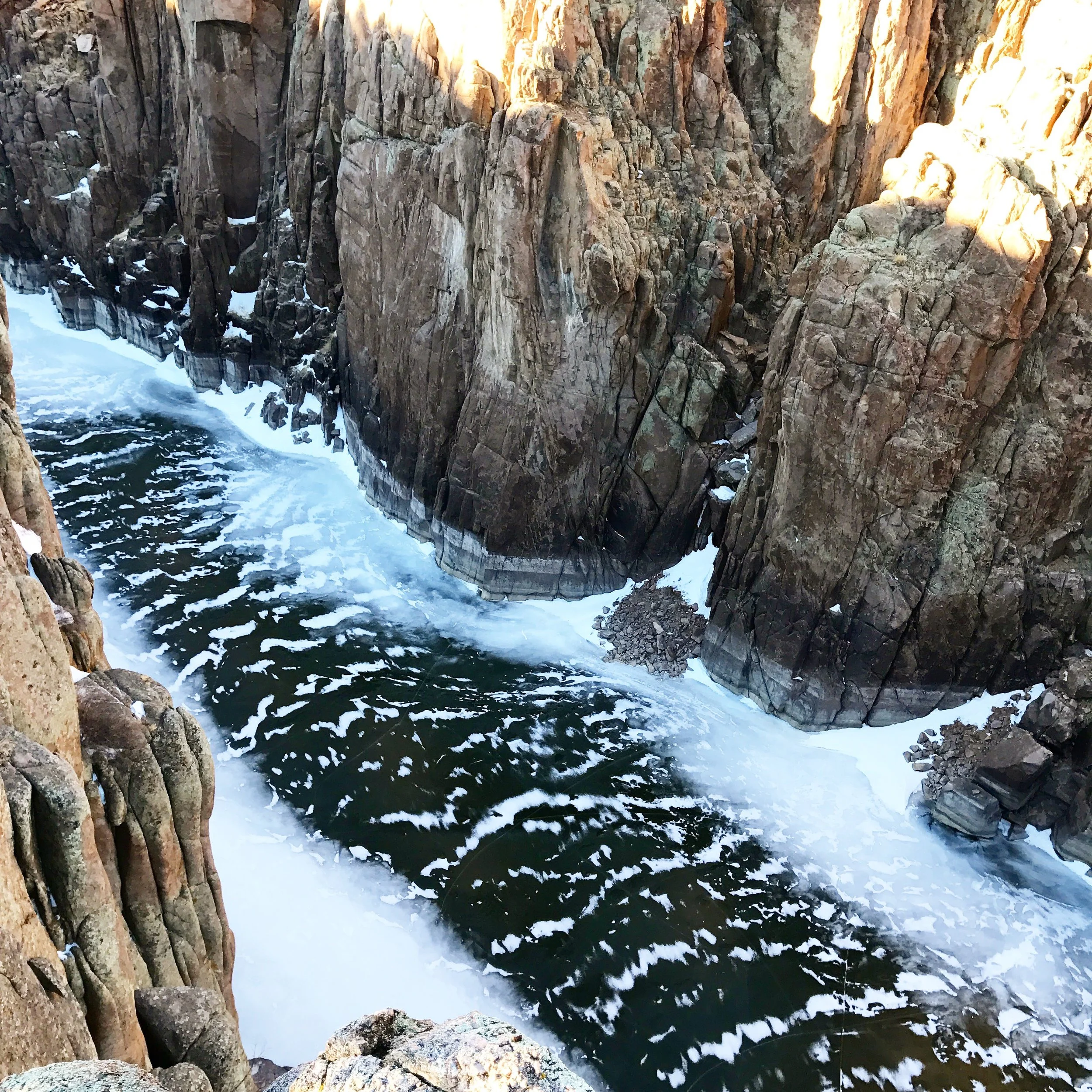 Rocky canyon with water rushing through and foam on the surface