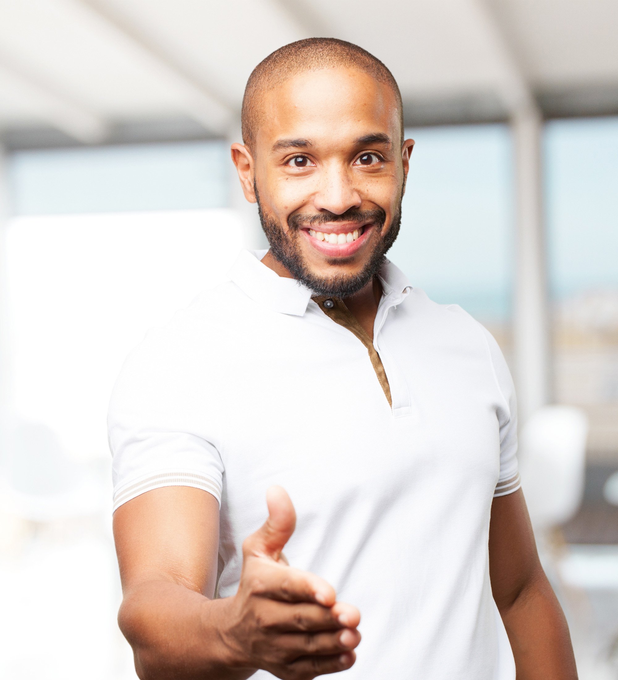 Smiling man giving a thumbs up indoors, with windows and a bright background.