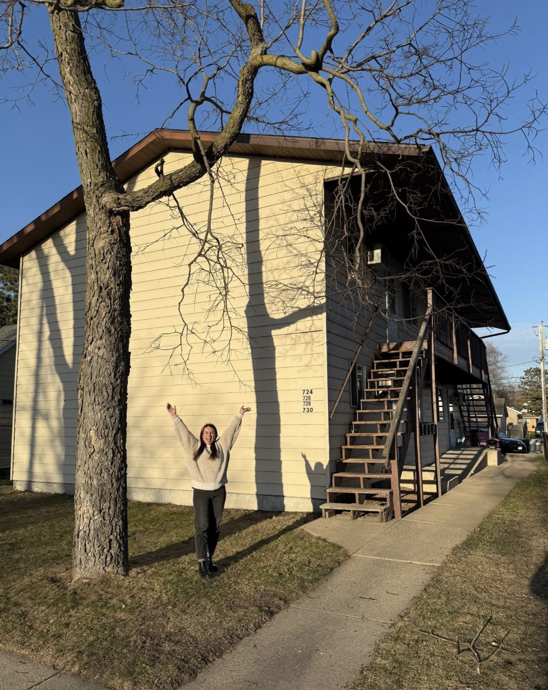 First-time home buyer standing in front of their first investment property after closing