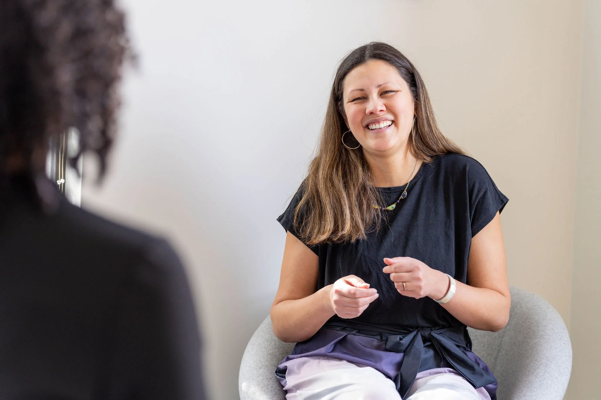 Photo of Hannah smiling and talking to an unknown person in the foreground.