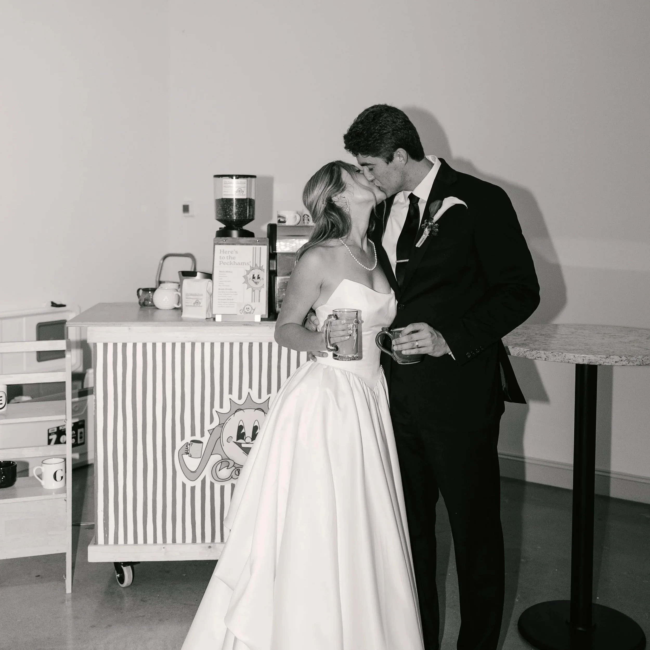 Married Couple kissing with thrifted mugs in front of Joy Cart Coffee