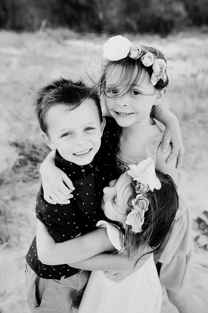 A portrait photo of three children hugging outdoors by Lee Burgess from Love and Life Photography