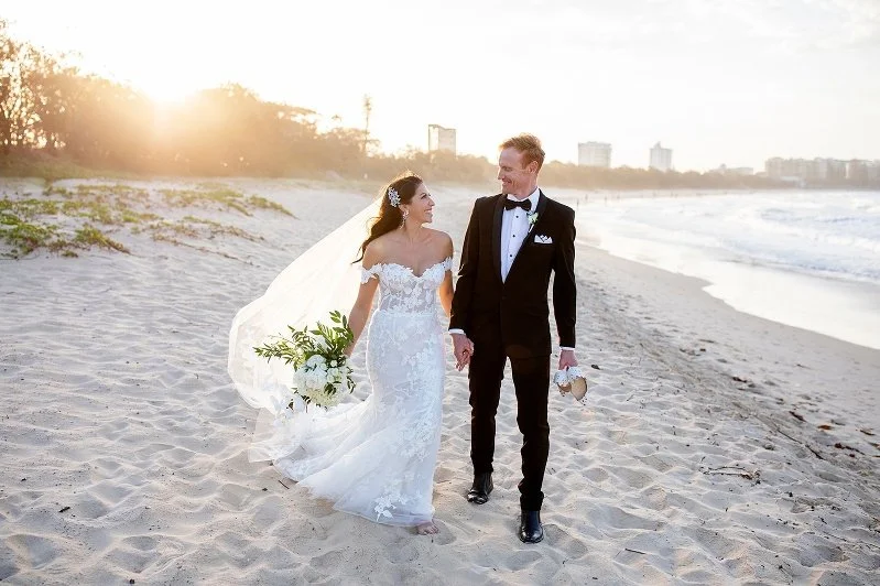 Bride and groom walking on the beach at sunset photo by Lee Burgess from Love and Life Photography 