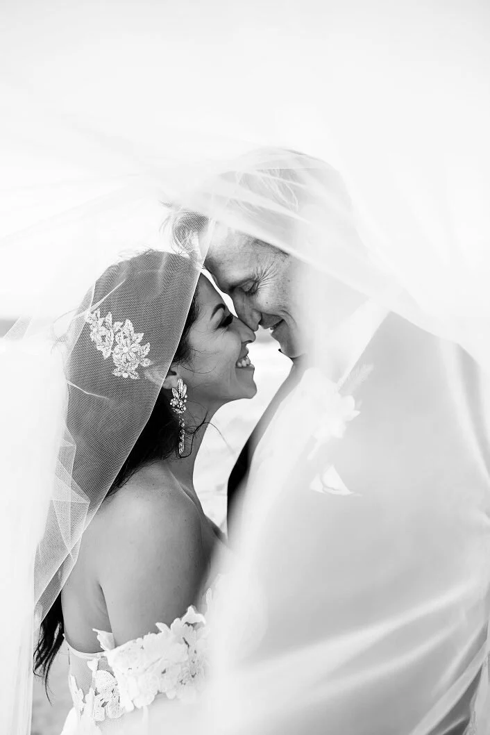 Black and white photo of a bride and groom under a wedding veil by Lee Burgess from Love and Life Photography 