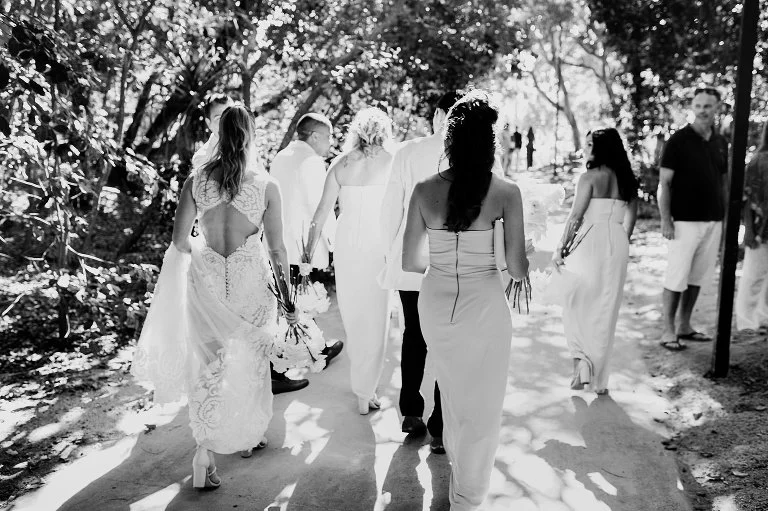 A wedding photo of a group of people walking on a path in a park or garden by Lee Burgess from Love and Life Photography 