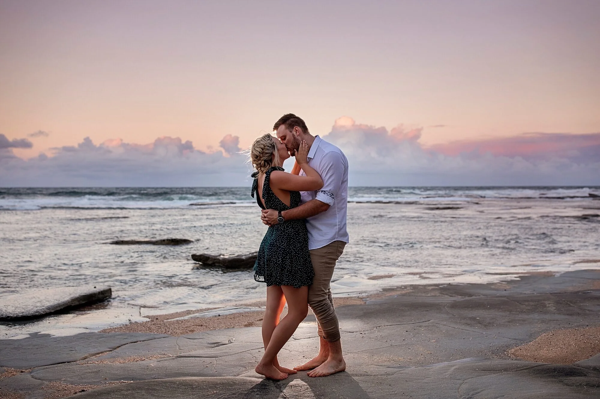 A portrait photo of a couple kissing on the beach during sunset, with the ocean in the background by Lee Burgess from Love and Life Photography