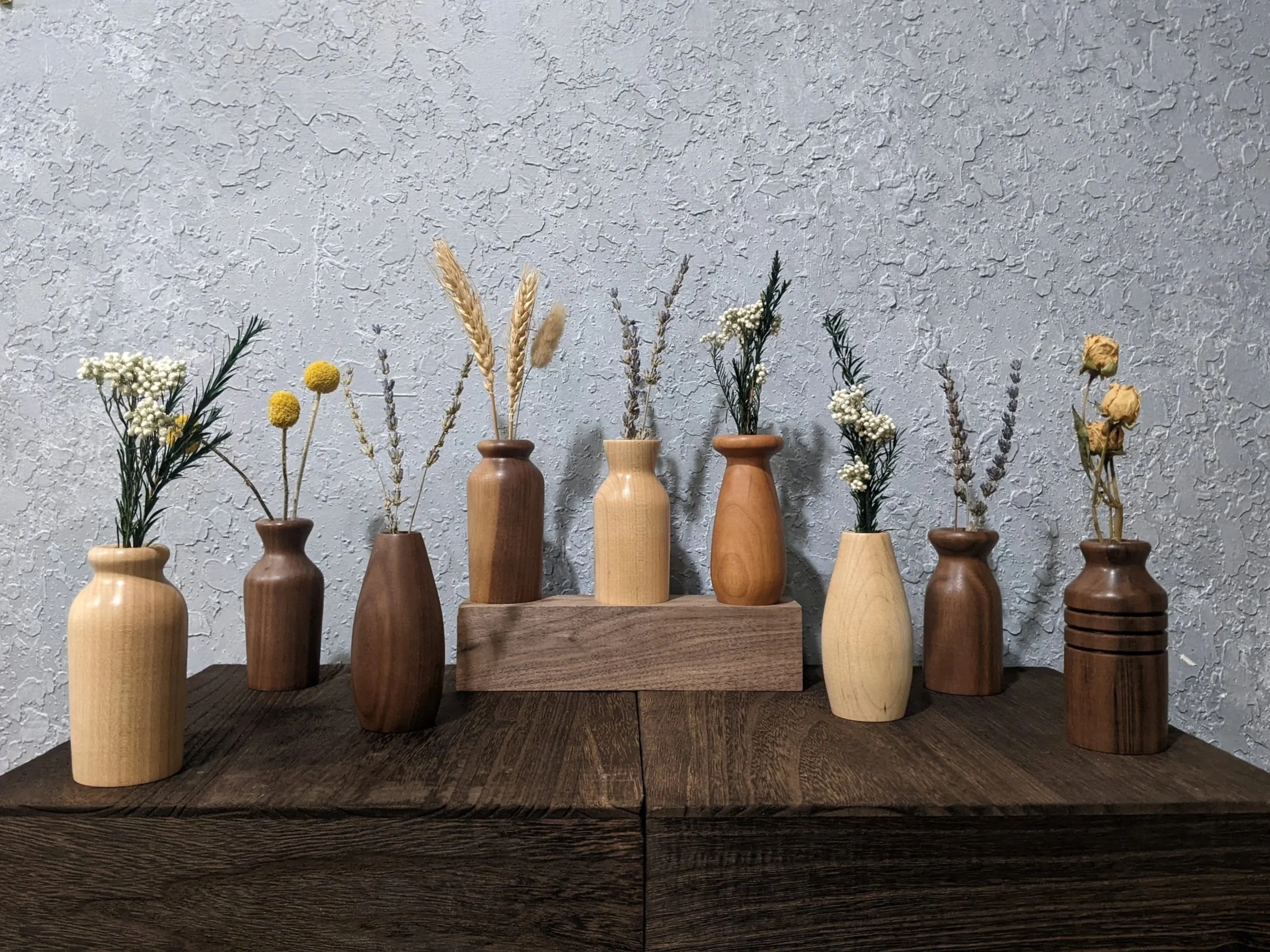 A variety of dry bouquet twig vases in different styles made from walnut, maple, and cherry hardwood.