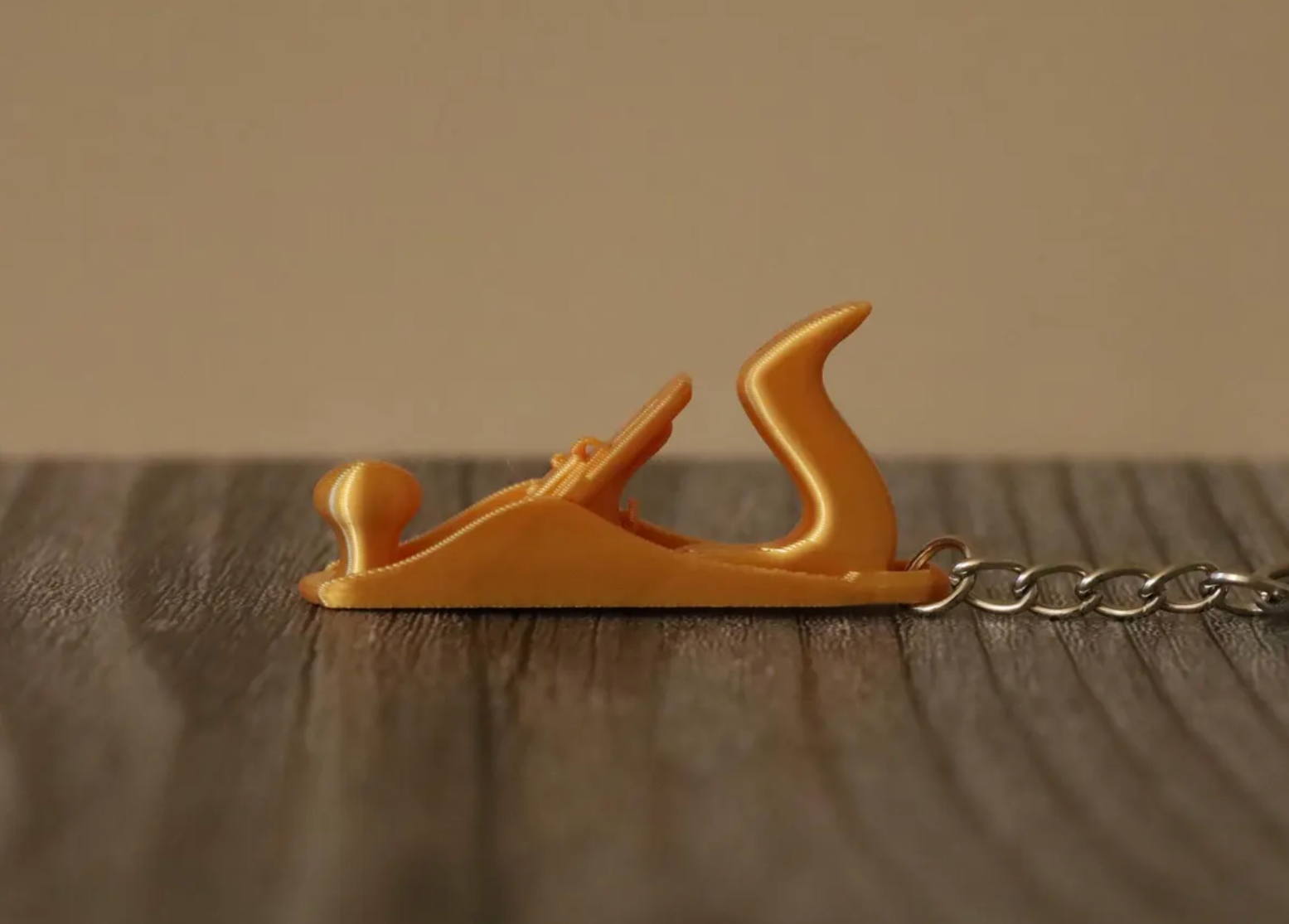Gold colored keychain that looks like a woodworking hand plane