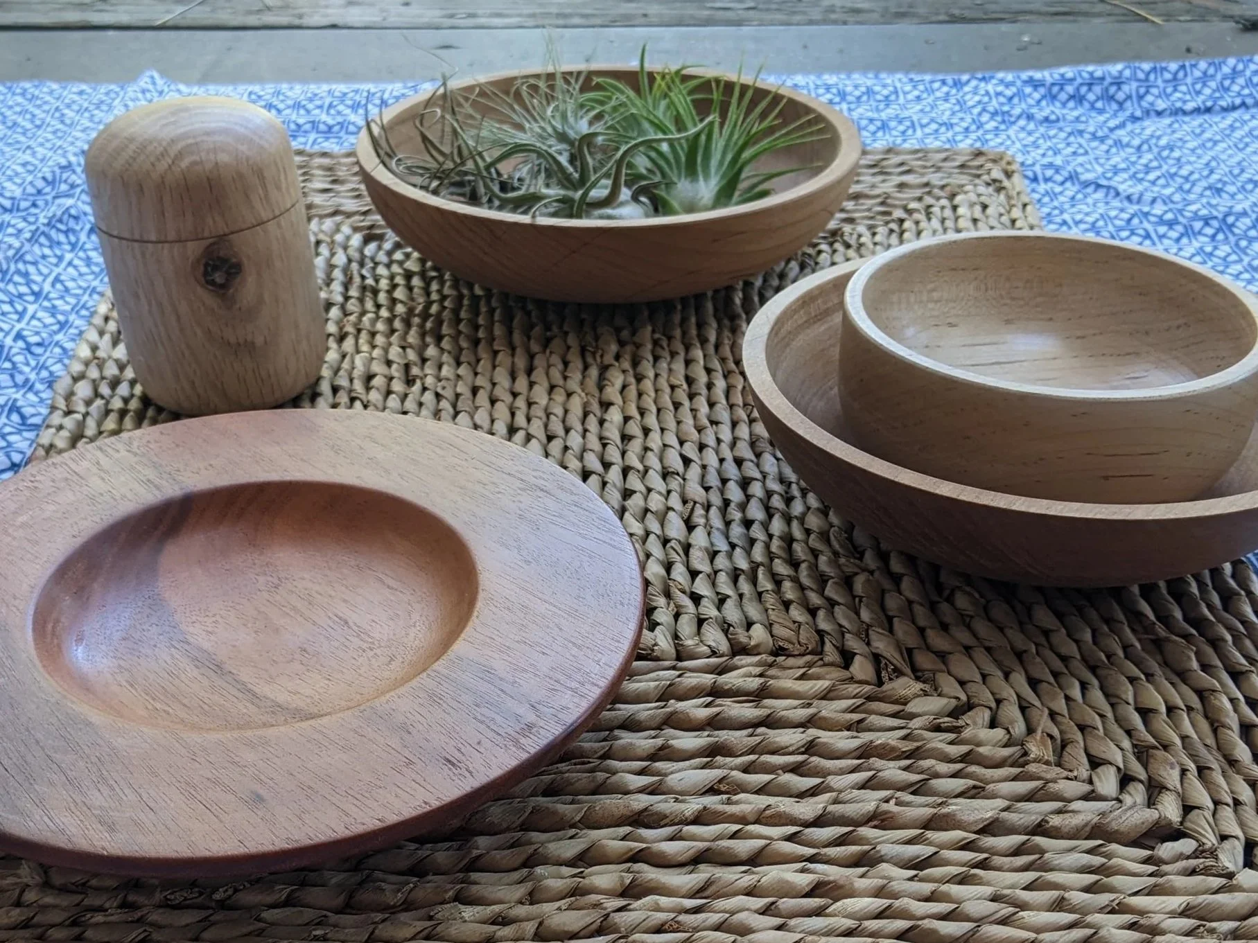Table display including hand turned wood items. There are 3 bowls, a platter, and one lidded capsule box.
