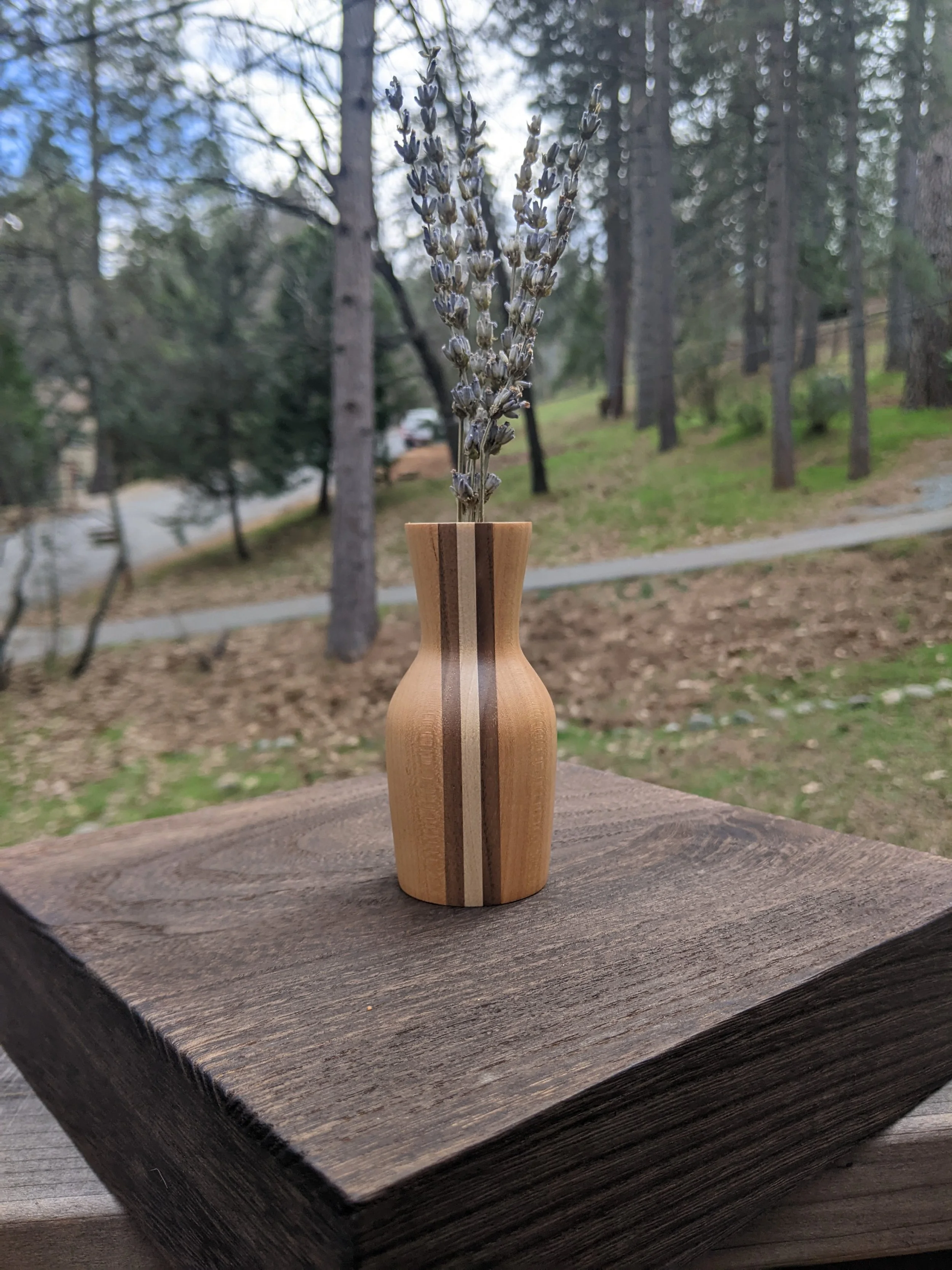 A modern style small dry bouquet vase. It is laminated from multiple woods including cherry, walnut, and maple.