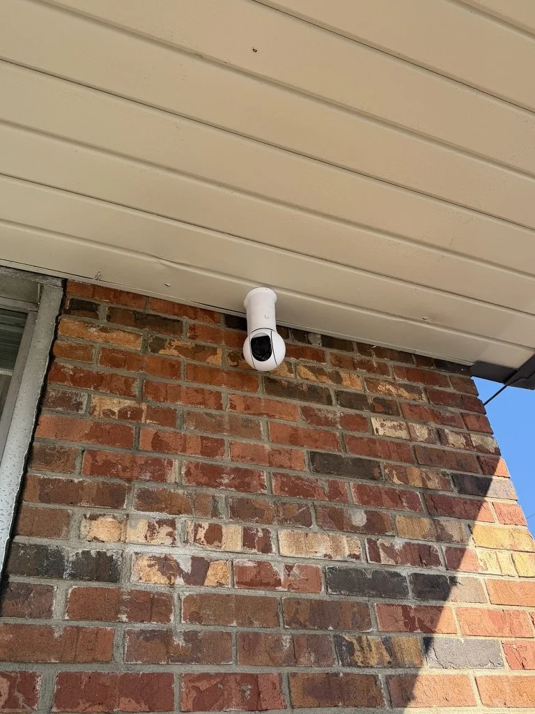 Security camera mounted under the eaves of a house with brick wall exterior