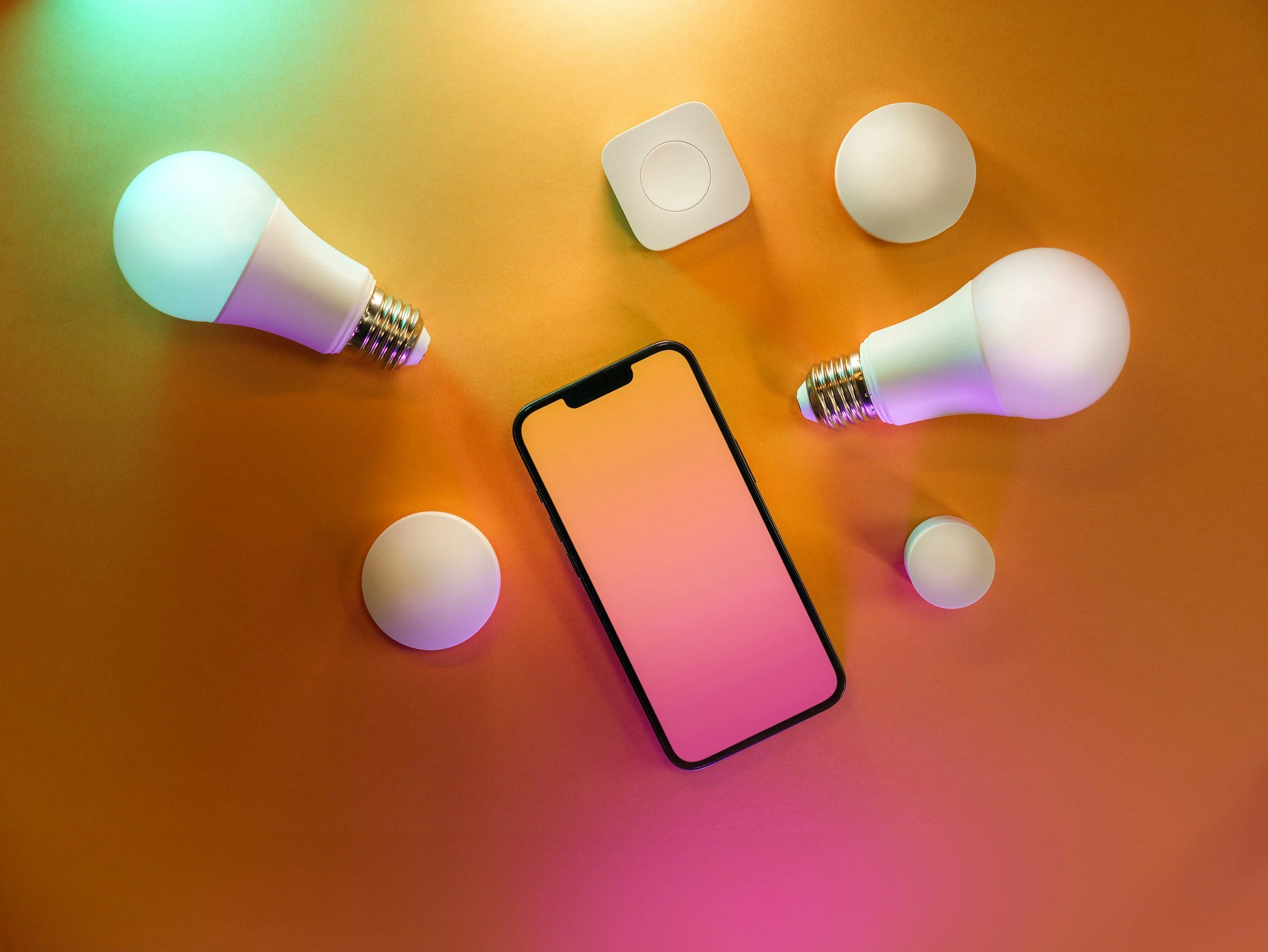 Colorful smartphone on orange background surrounded by two smart light bulbs and two smart bulbs, with a smart switch in the top center.