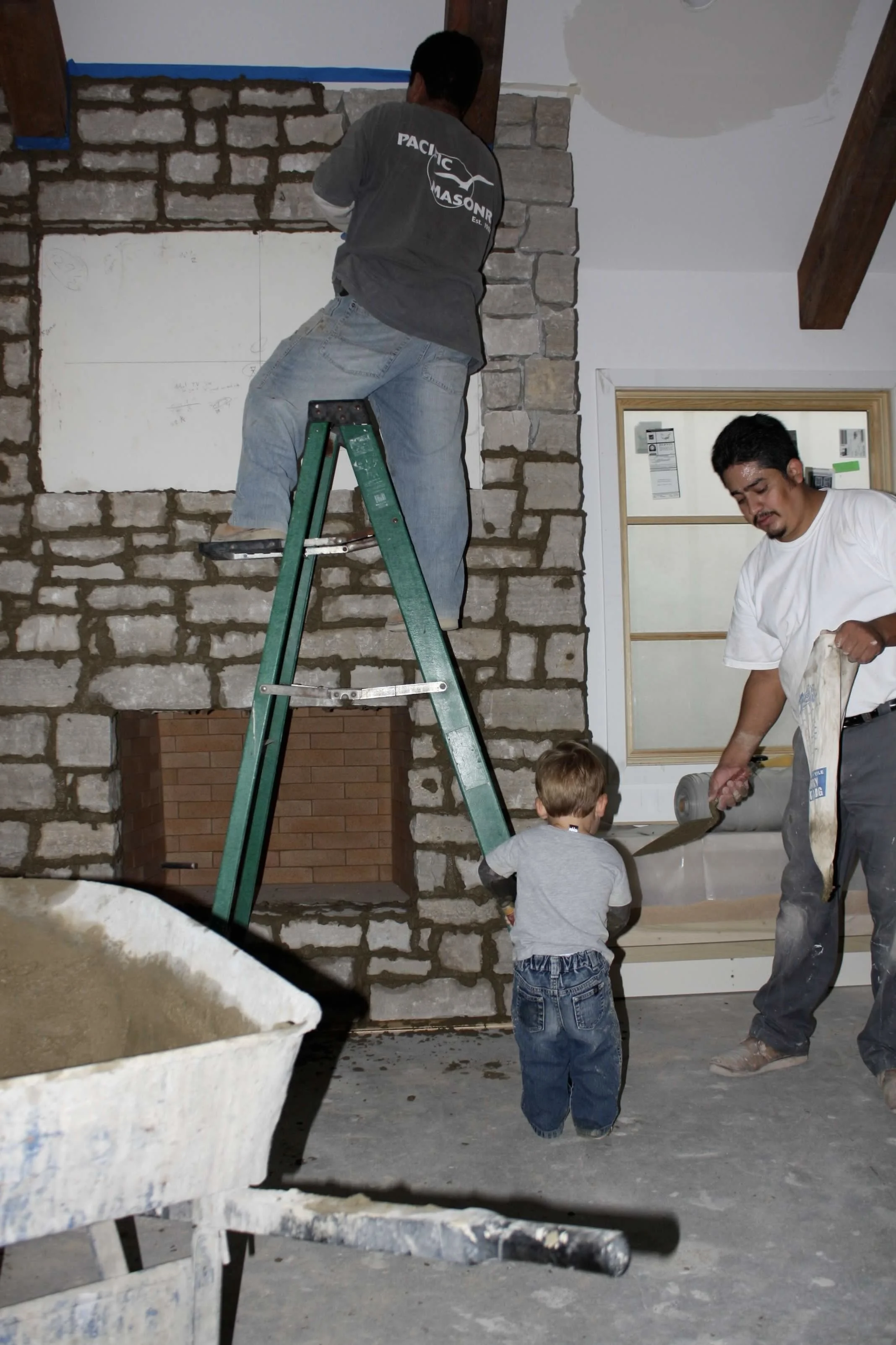 October 10th, 2010 Miguel Pelaez teaching a child the basics of grouting a stone fireplace.