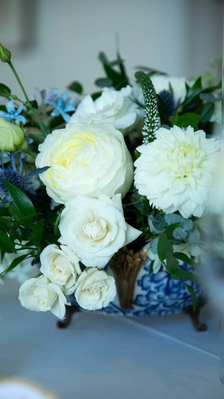 Macro detail shot of a wedding bouquet featuring cream garden roses, blue thistles, and fresh eucalyptus leaf accents.