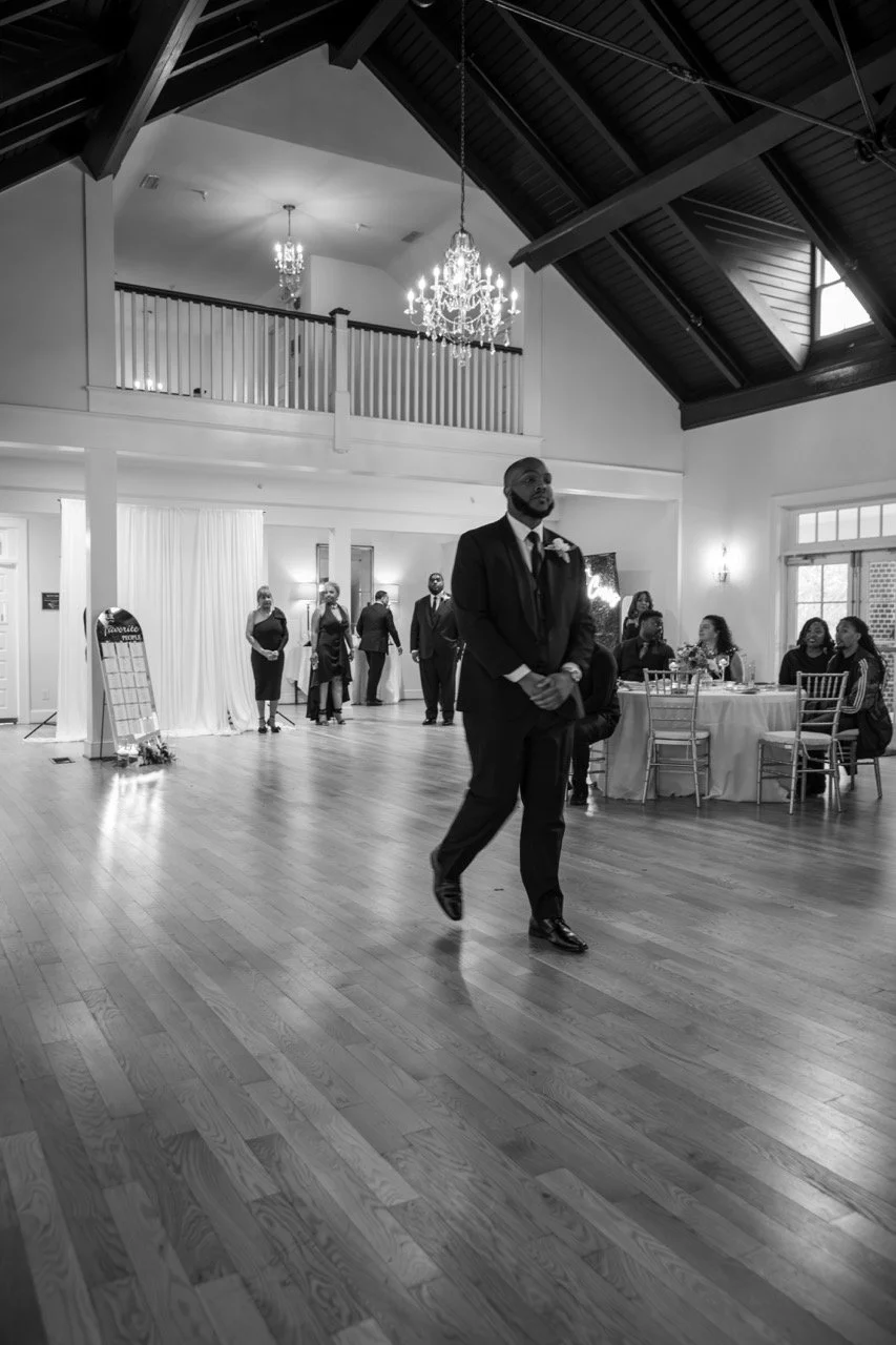 Groom Tristan walking across the hardwood dance floor inside the reception hall at the Woman's Club of Portsmouth.